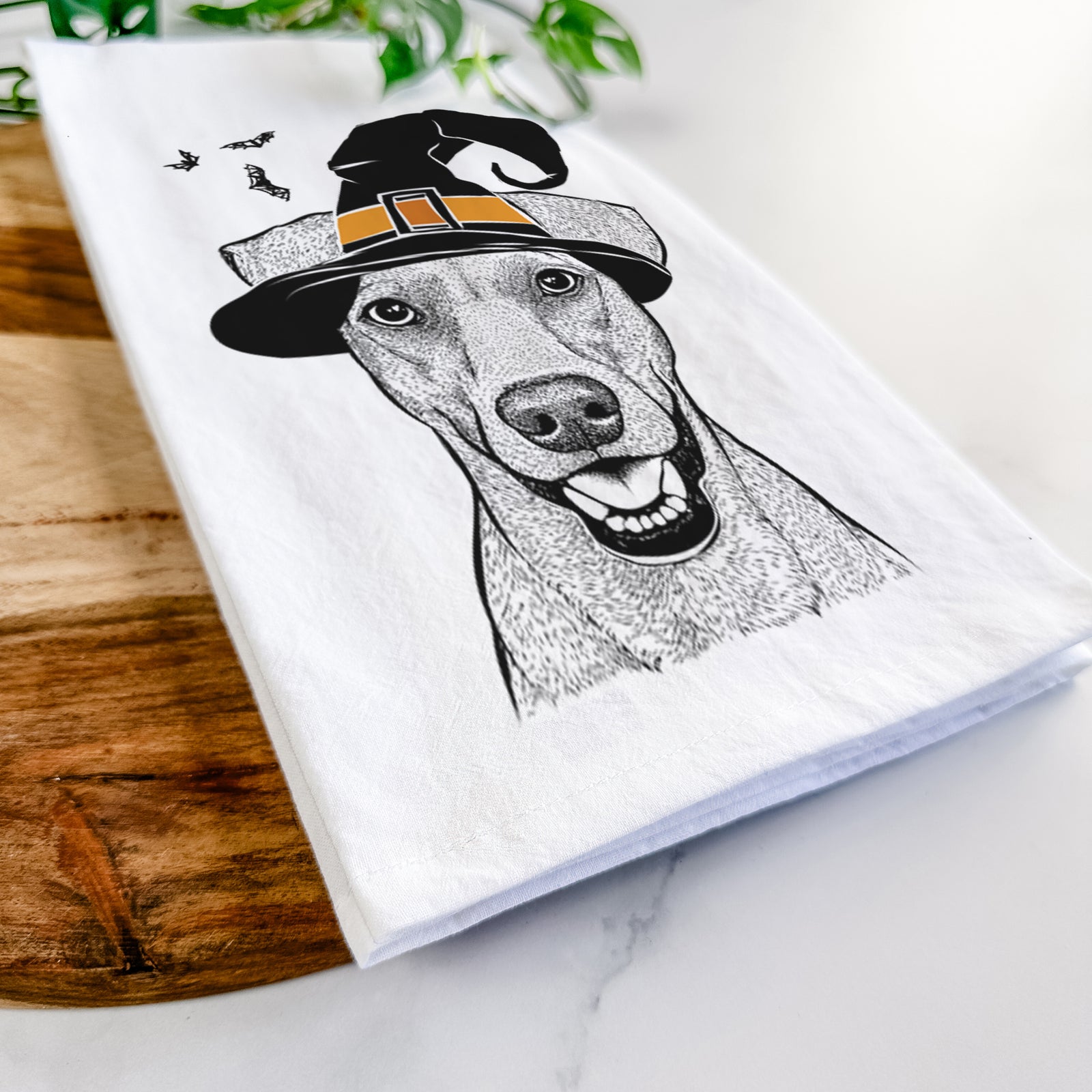 Hand-drawn sketch of Willow the German Pinscher wearing a witch hat on a tea towel