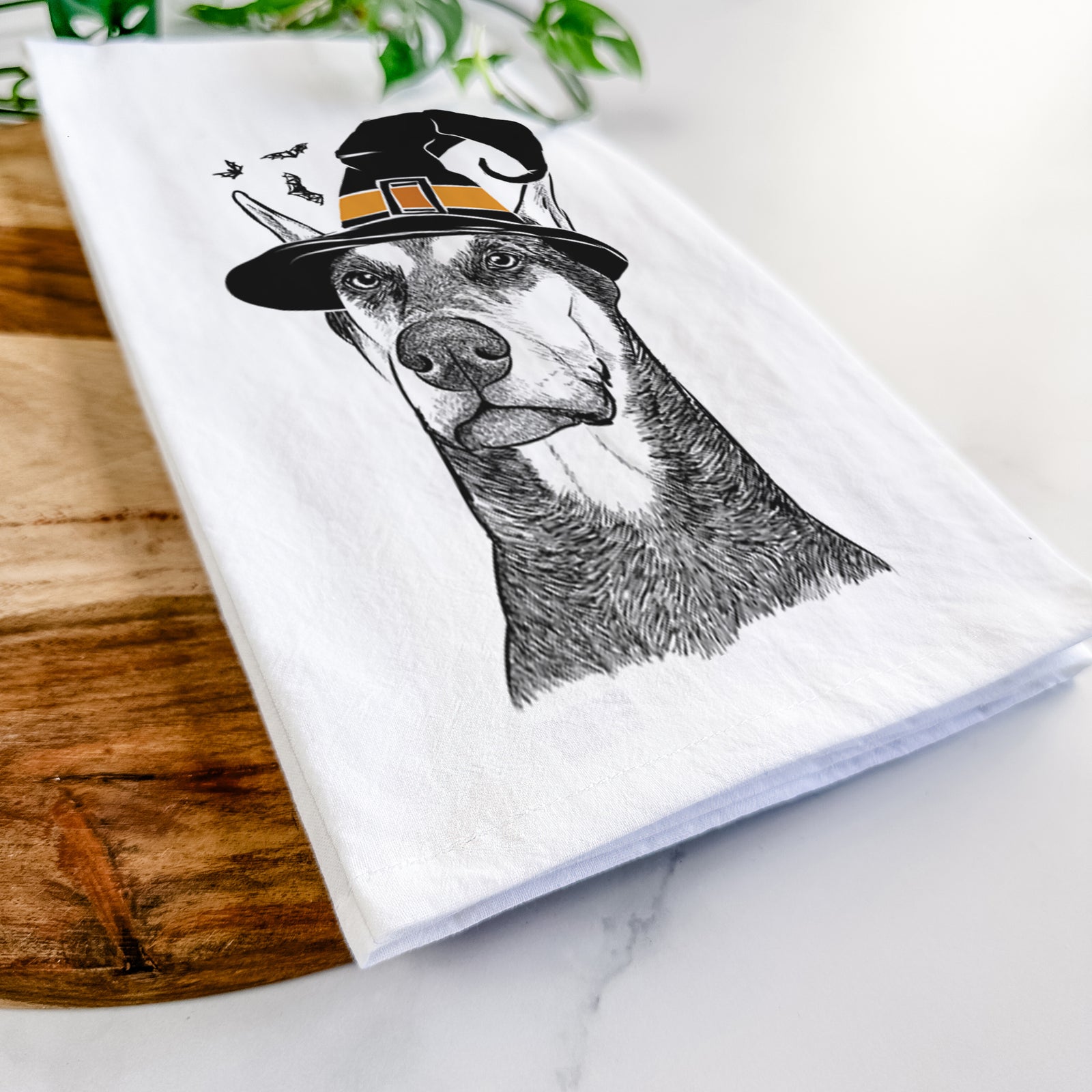 Hand-drawn sketch of Zeus the Doberman Pinscher wearing a witch hat on a tea towel