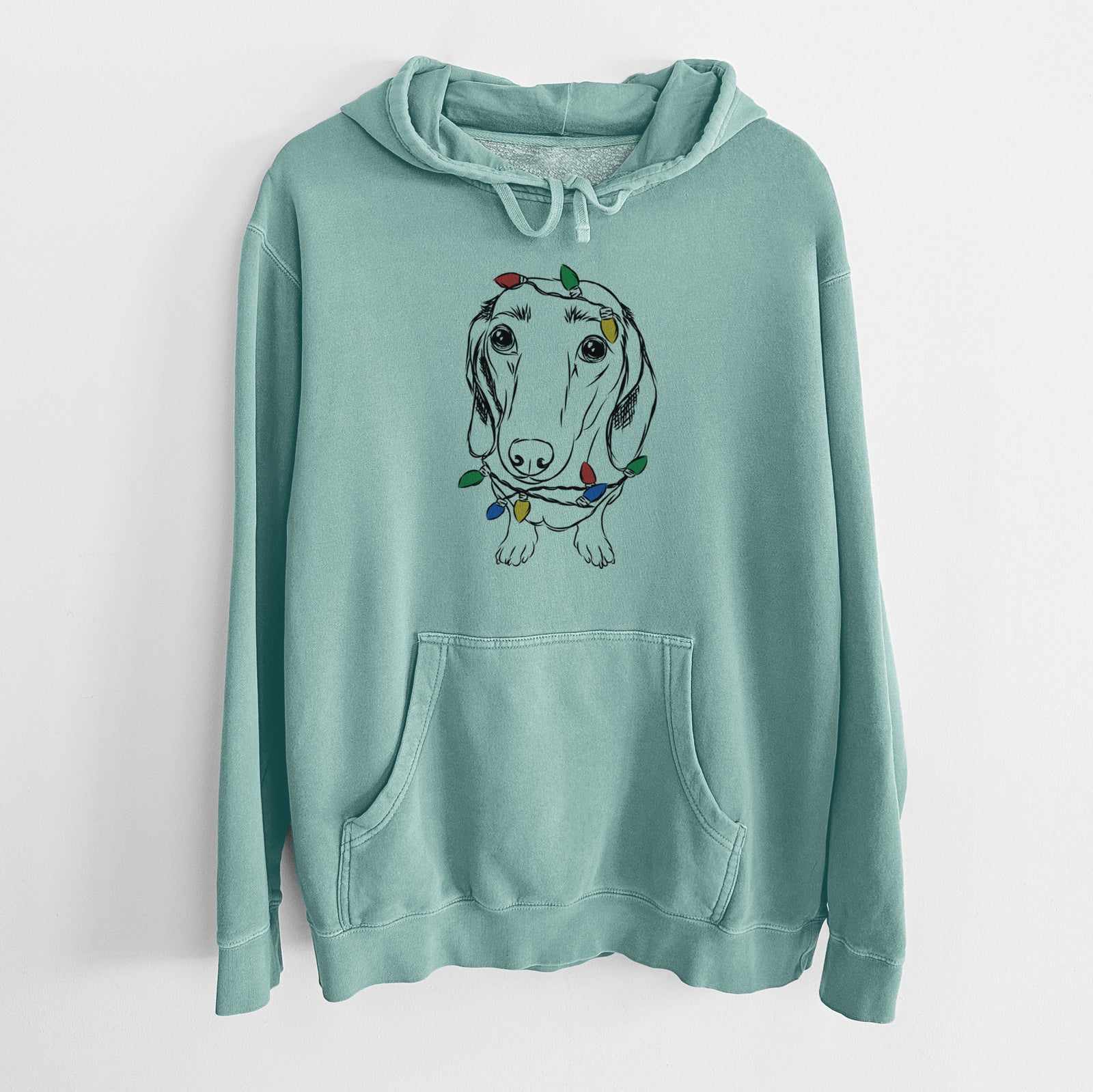 Hand-drawn sketch of Annabelle the Dachshund wrapped in Christmas lights on a Mint Unisex pigment dyed hoodie