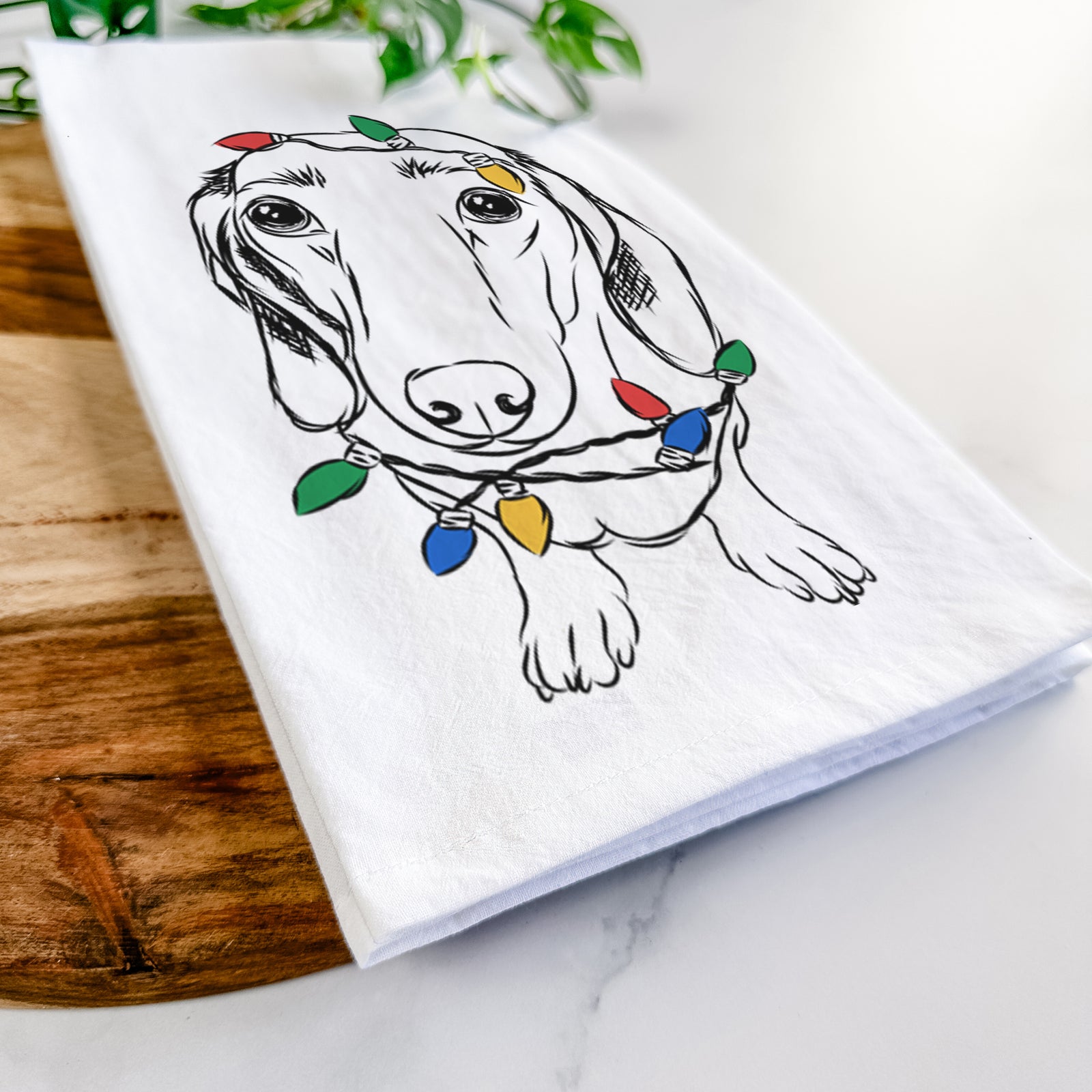 Hand-drawn sketch of Annabelle the Dachshund wrapped in Christmas lights on a tea towel