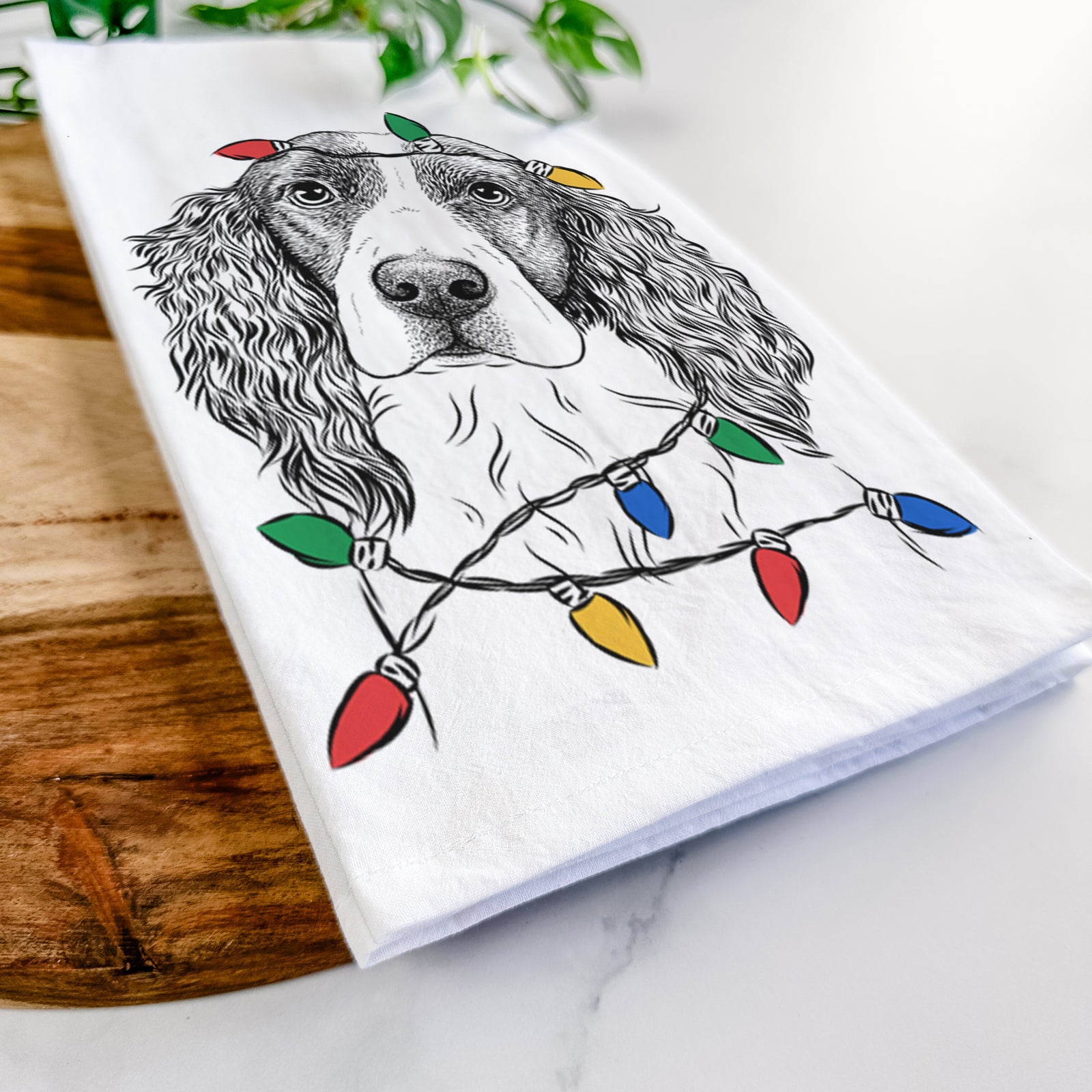 Hand-drawn sketch of Annie the English Springer Spaniel wrapped in Christmas lights on a tea towel