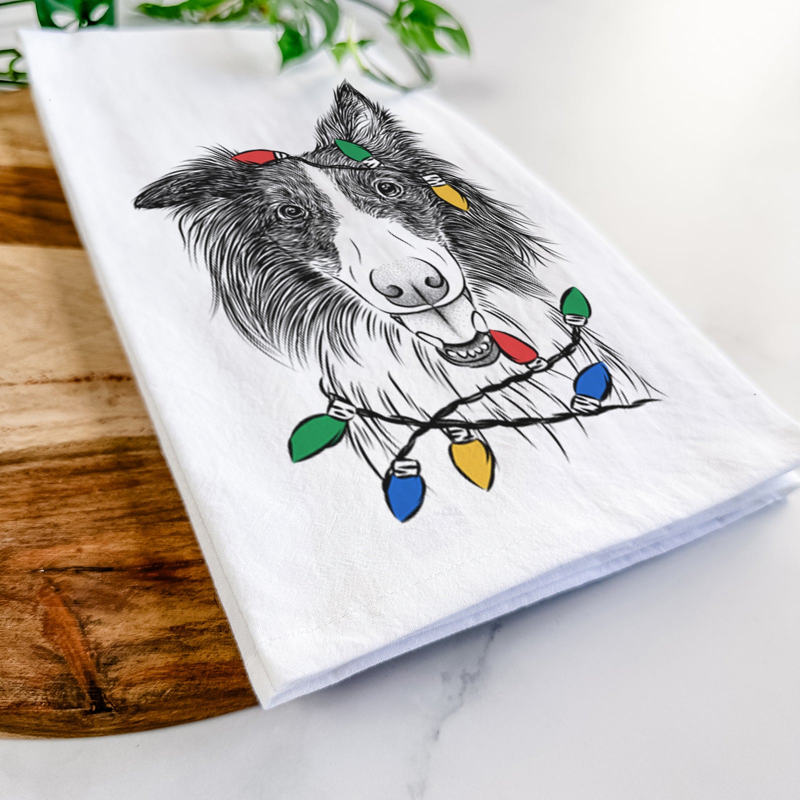 Hand-drawn sketch of Archie the Silken Windhound wrapped in Christmas lights on a tea towel