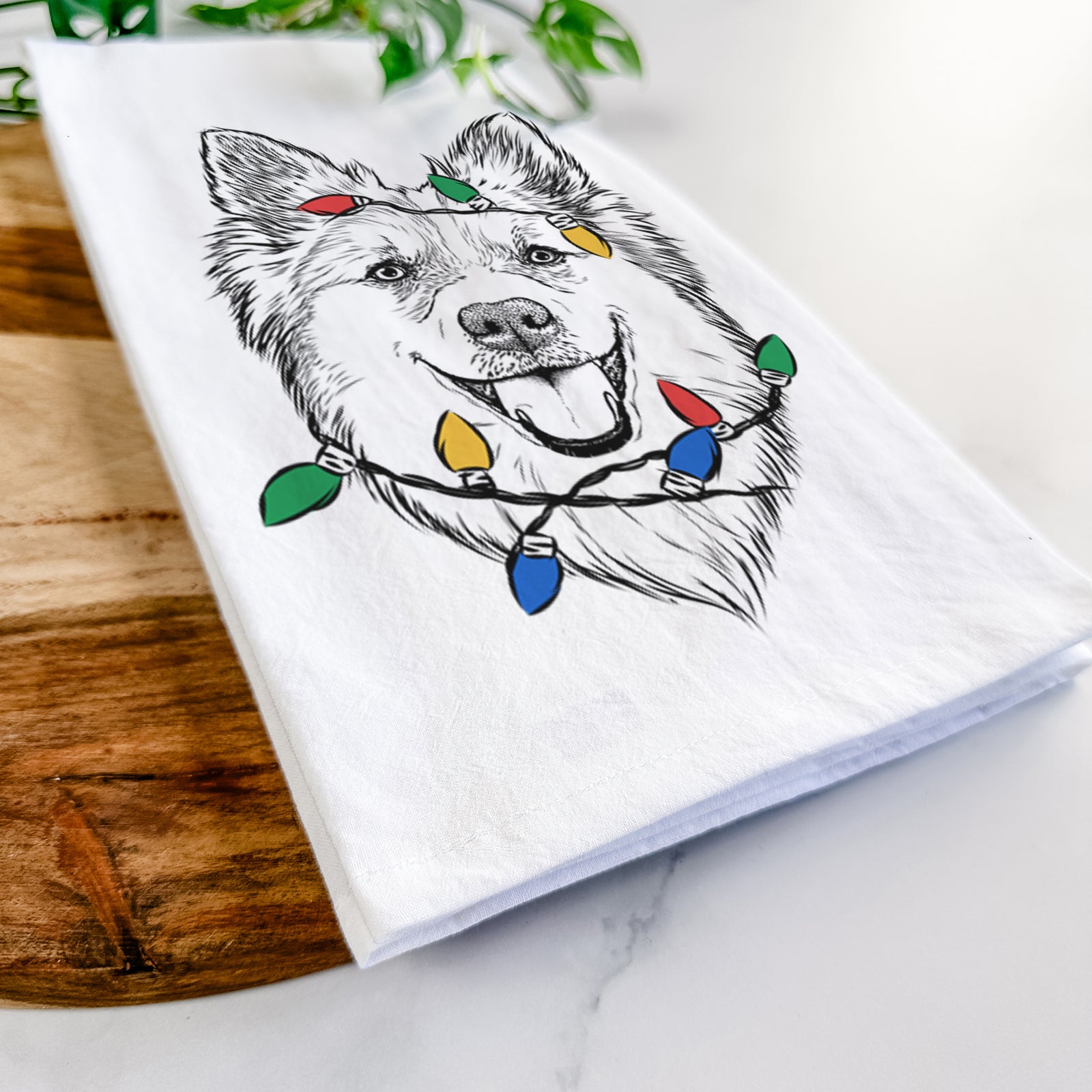 Hand-drawn sketch of Ari the Icelandic Sheepdog wrapped in Christmas lights on a tea towel