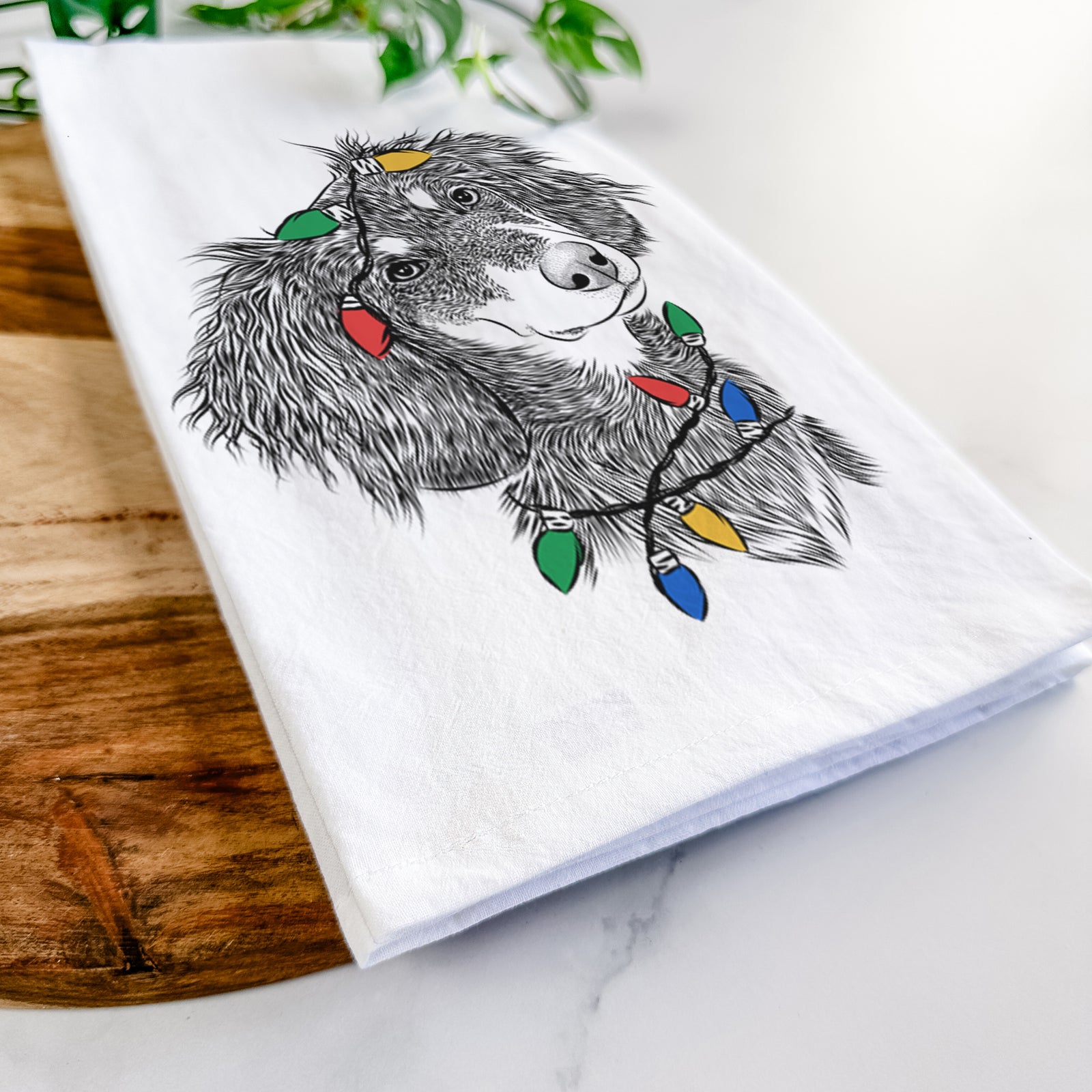 Hand-drawn sketch of Bailey the Long Haired Dachshund wrapped in Christmas lights on a tea towel