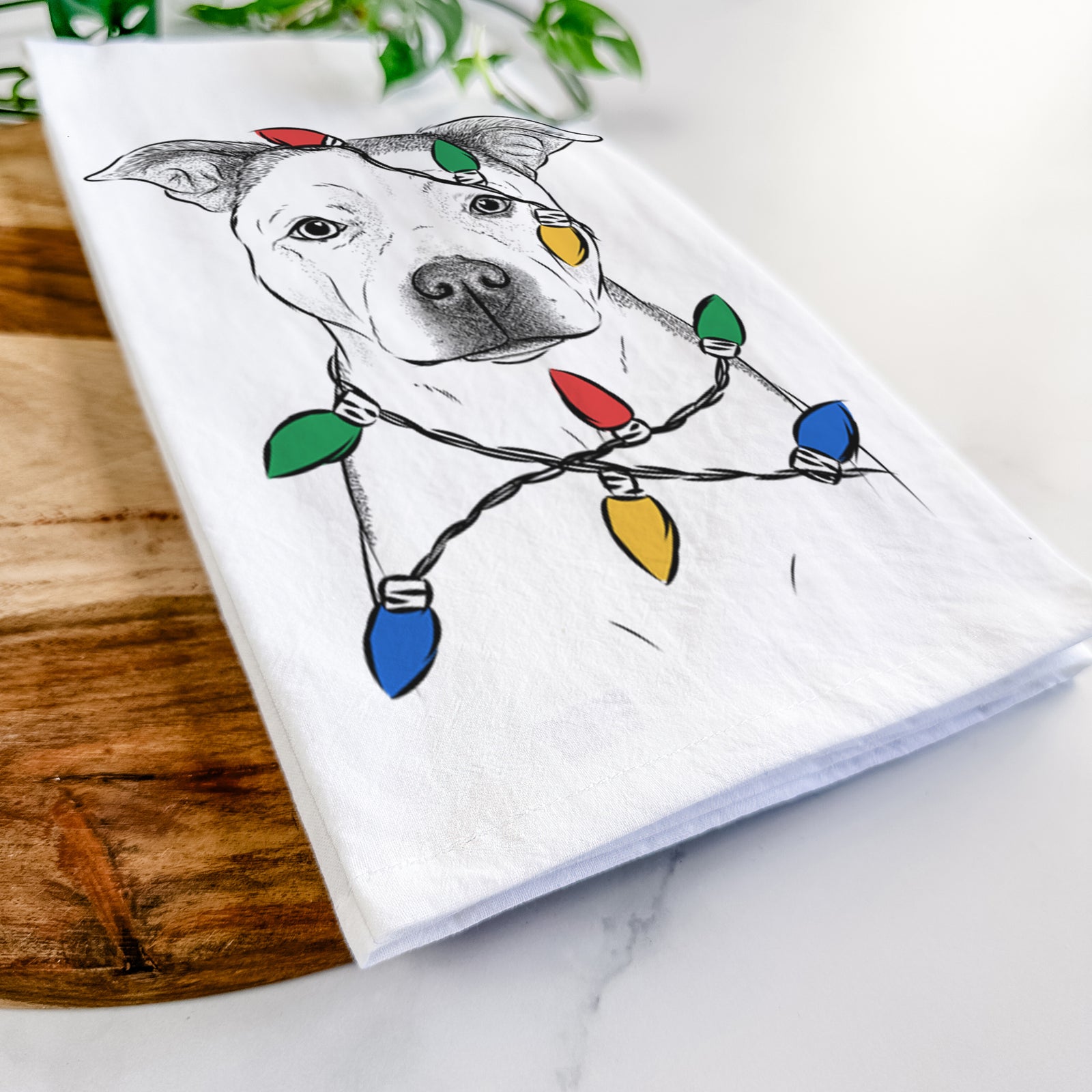 Hand-drawn sketch of Bailey the Pitbull wrapped in Christmas lights on a tea towel