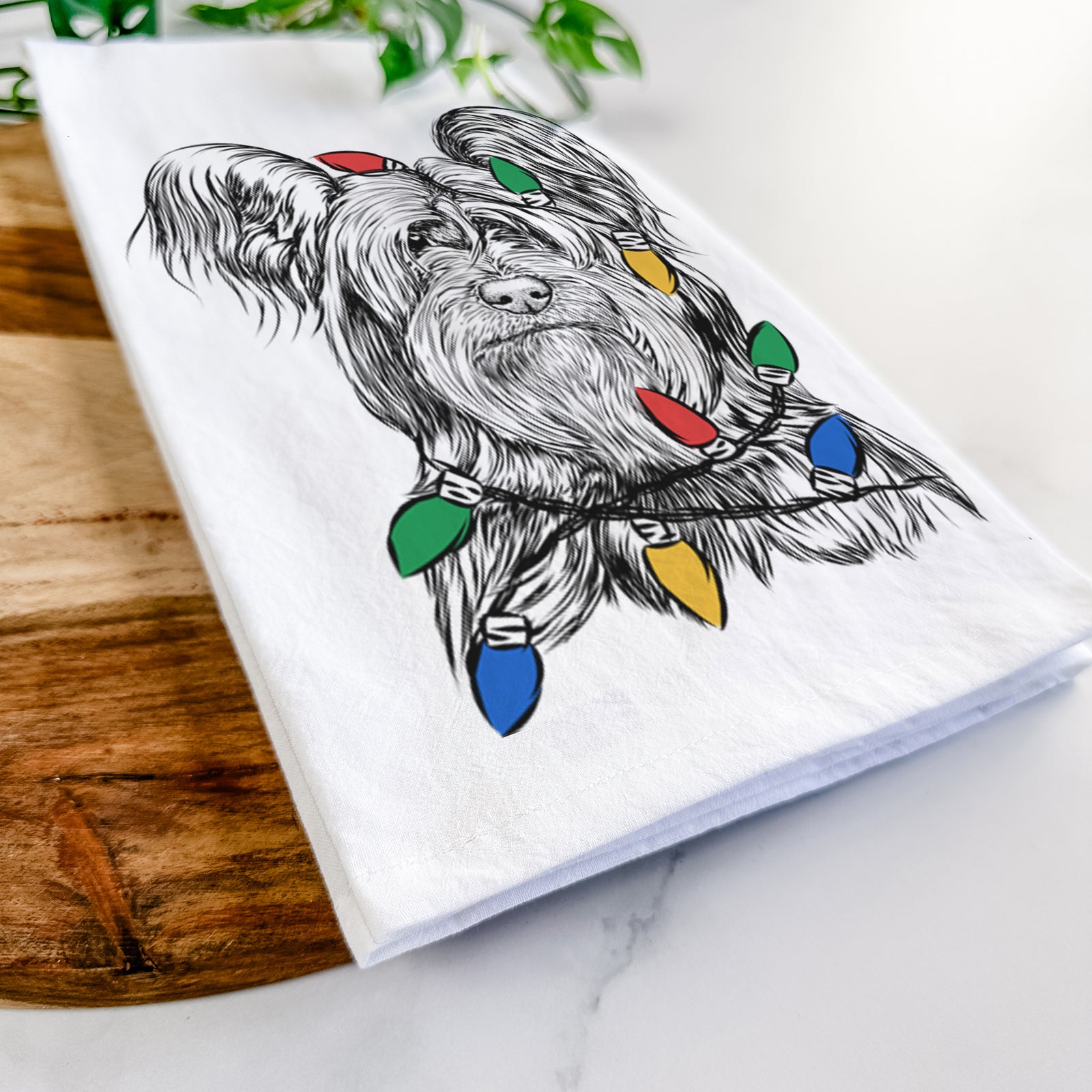 Hand-drawn sketch of Bandit the Skye Terrier wrapped in Christmas lights on a tea towel