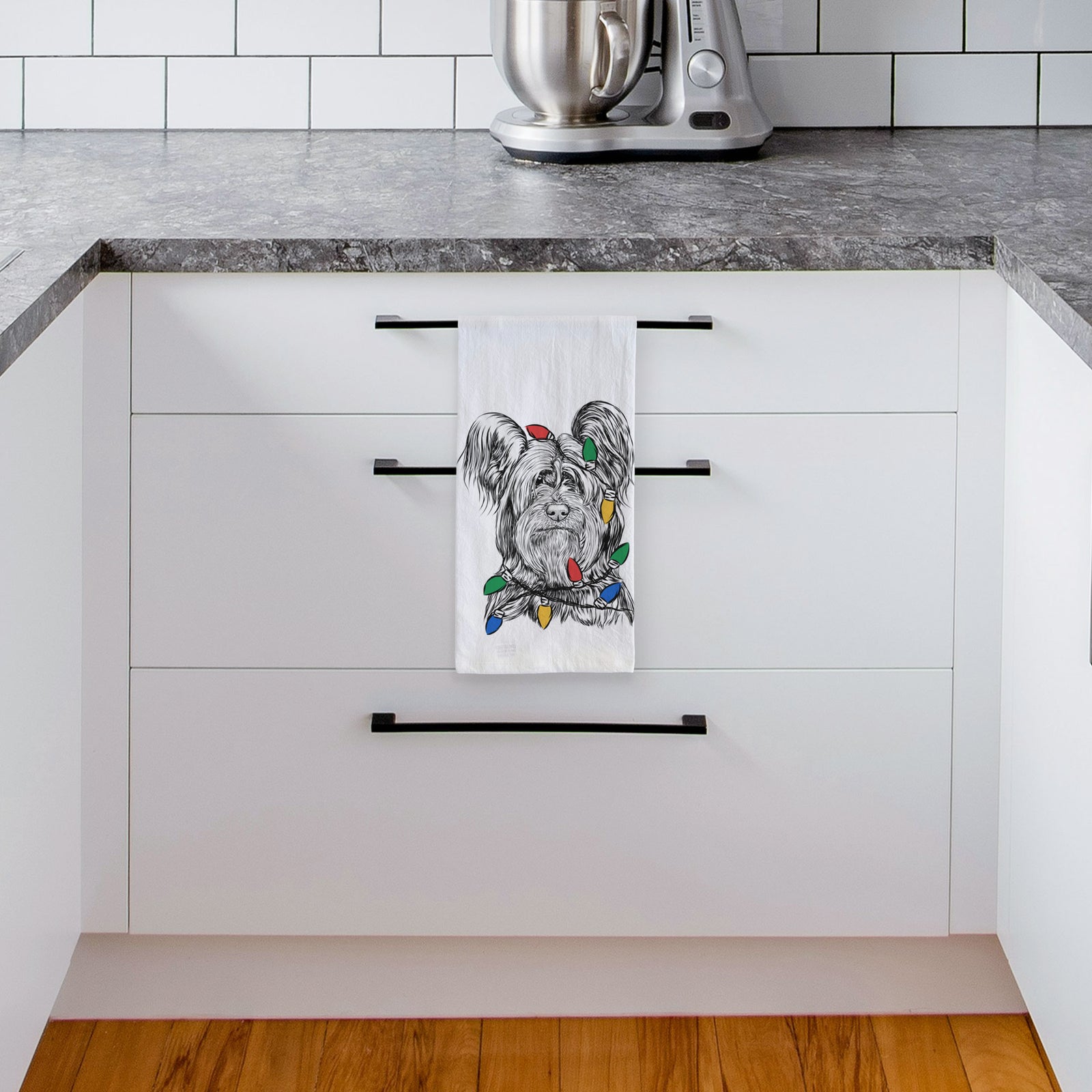 Hand-drawn sketch of Bandit the Skye Terrier wrapped in Christmas lights on a tea towel, hanging on an oven door in a kitchen
