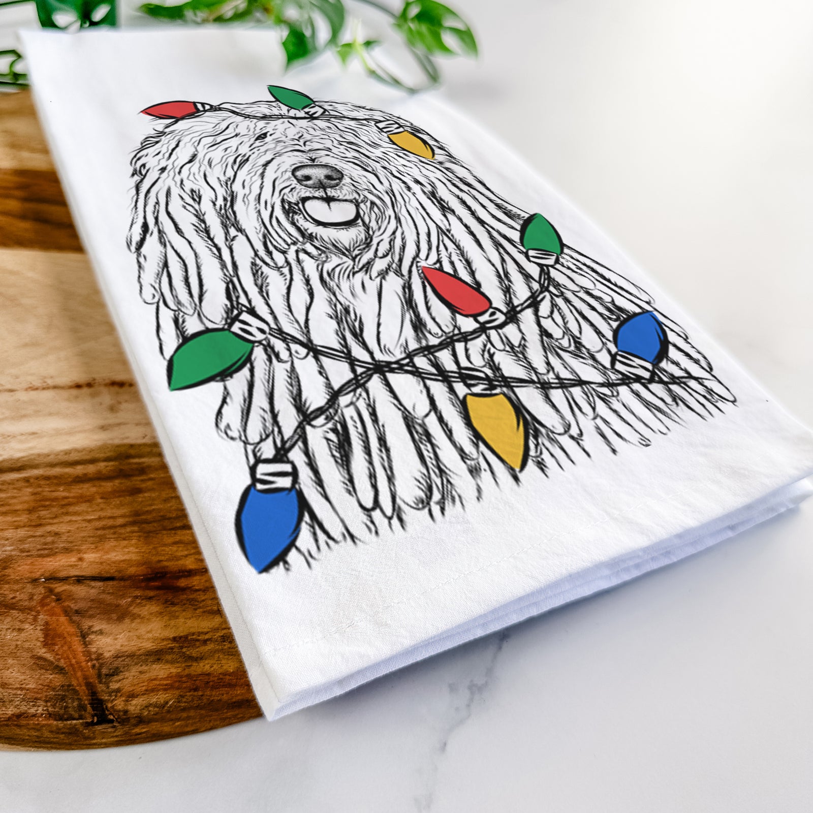Hand-drawn sketch of Barry the Komondor wrapped in Christmas lights on a tea towel