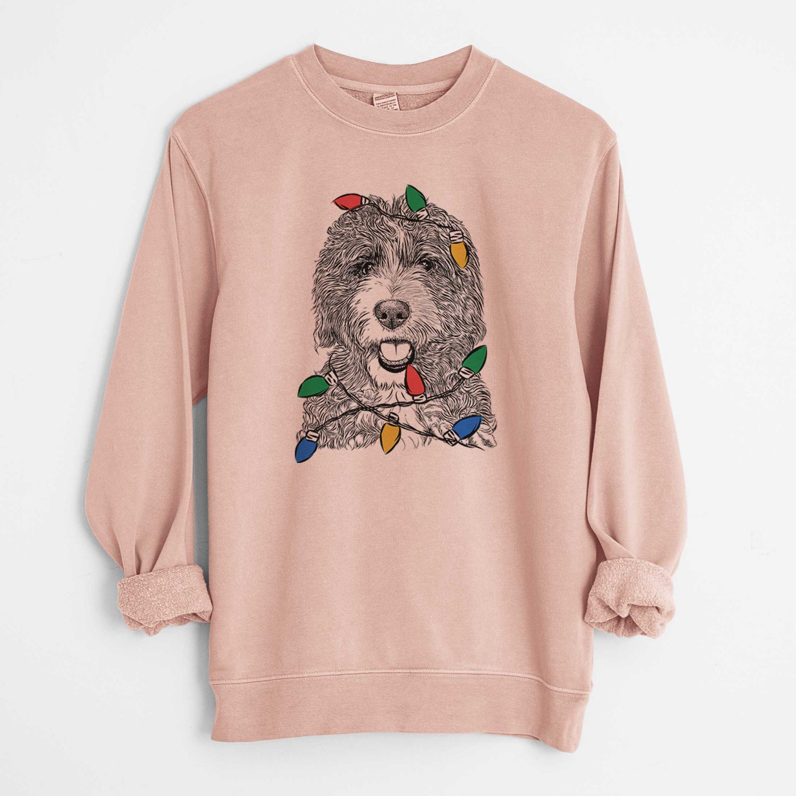 Hand-drawn sketch of Bash the Bernedoodle wrapped in Christmas lights on a Dusty Pink Unisex pigment dyed crew sweatshirt