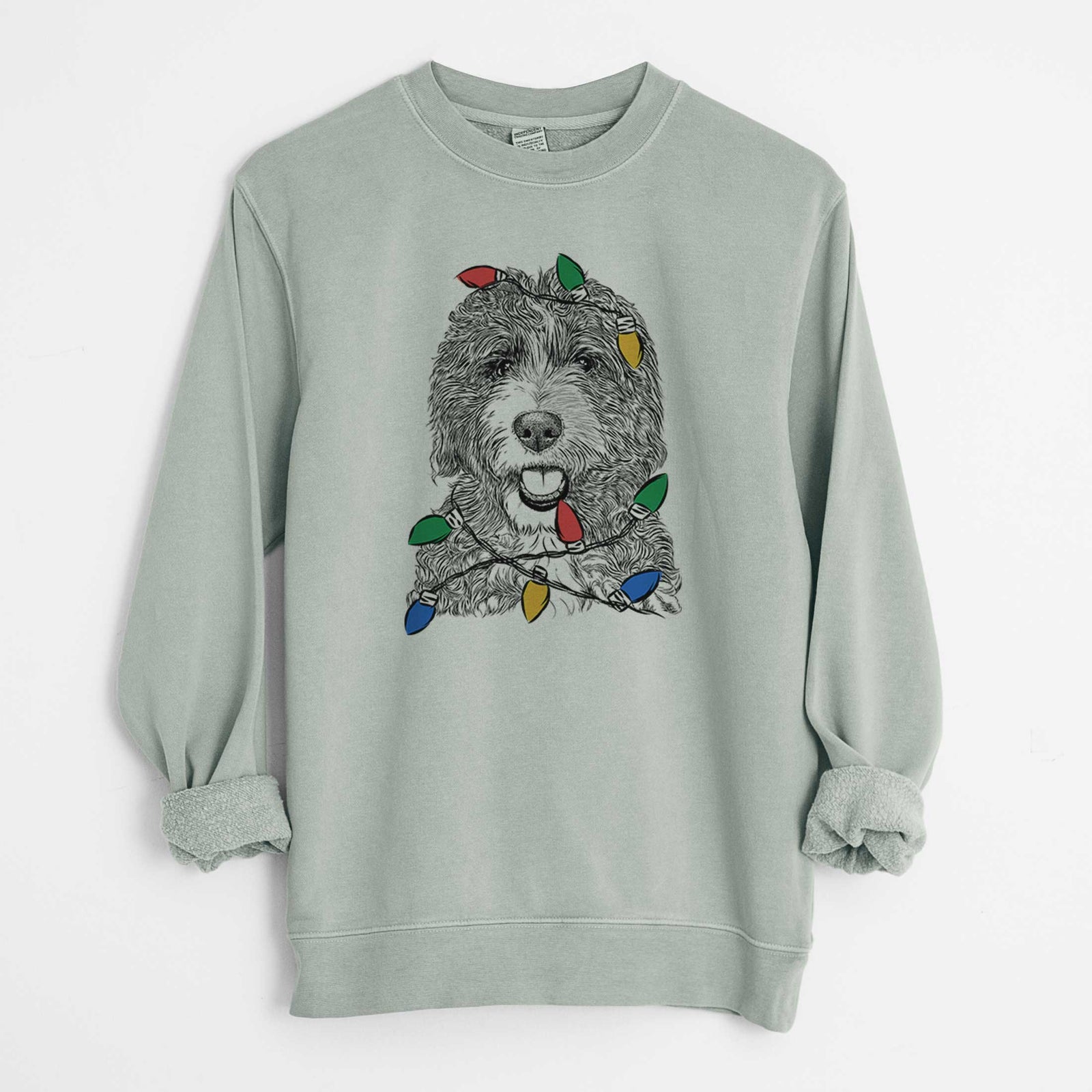 Hand-drawn sketch of Bash the Bernedoodle wrapped in Christmas lights on a Sage Unisex pigment dyed crew sweatshirt