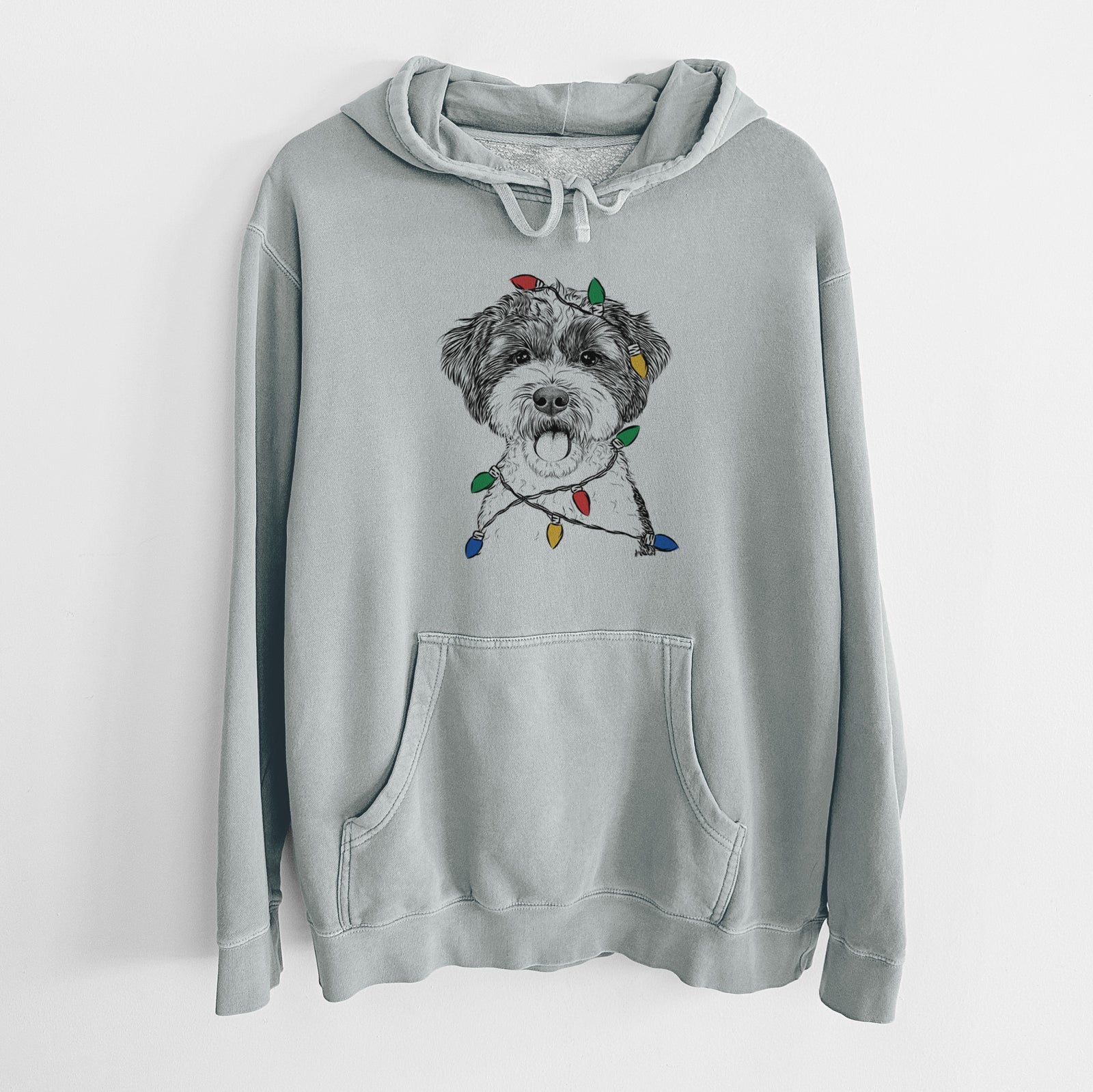 Hand-drawn sketch of Bella the Cockapoo wrapped in Christmas lights on a Sage Unisex pigment dyed hoodie
