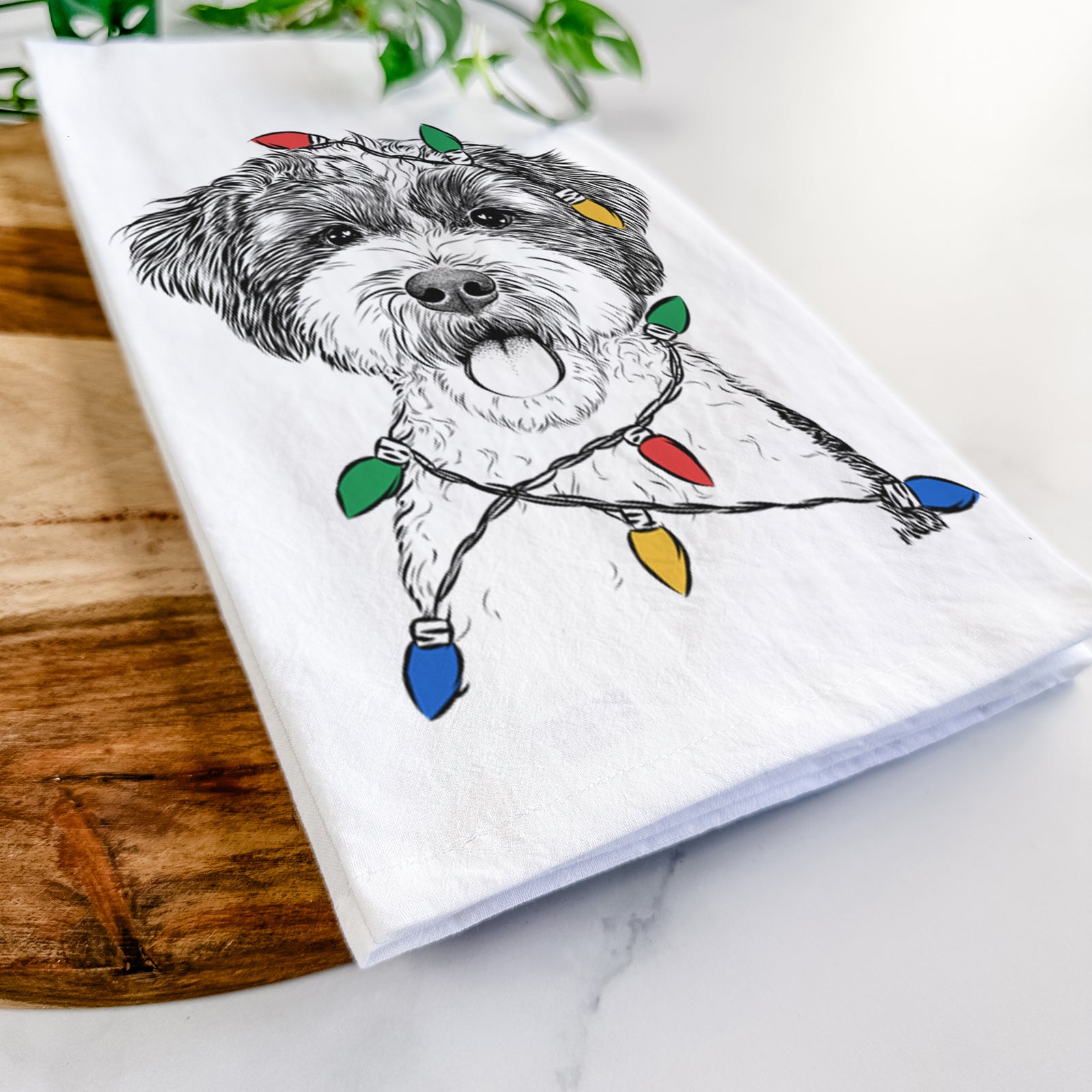 Hand-drawn sketch of Bella the Cockapoo wrapped in Christmas lights on a tea towel