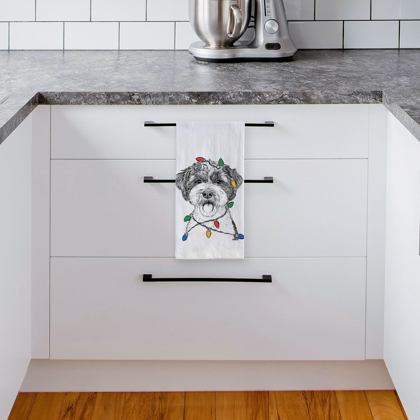 Hand-drawn sketch of Bella the Cockapoo wrapped in Christmas lights on a tea towel, hanging on an oven door in a kitchen