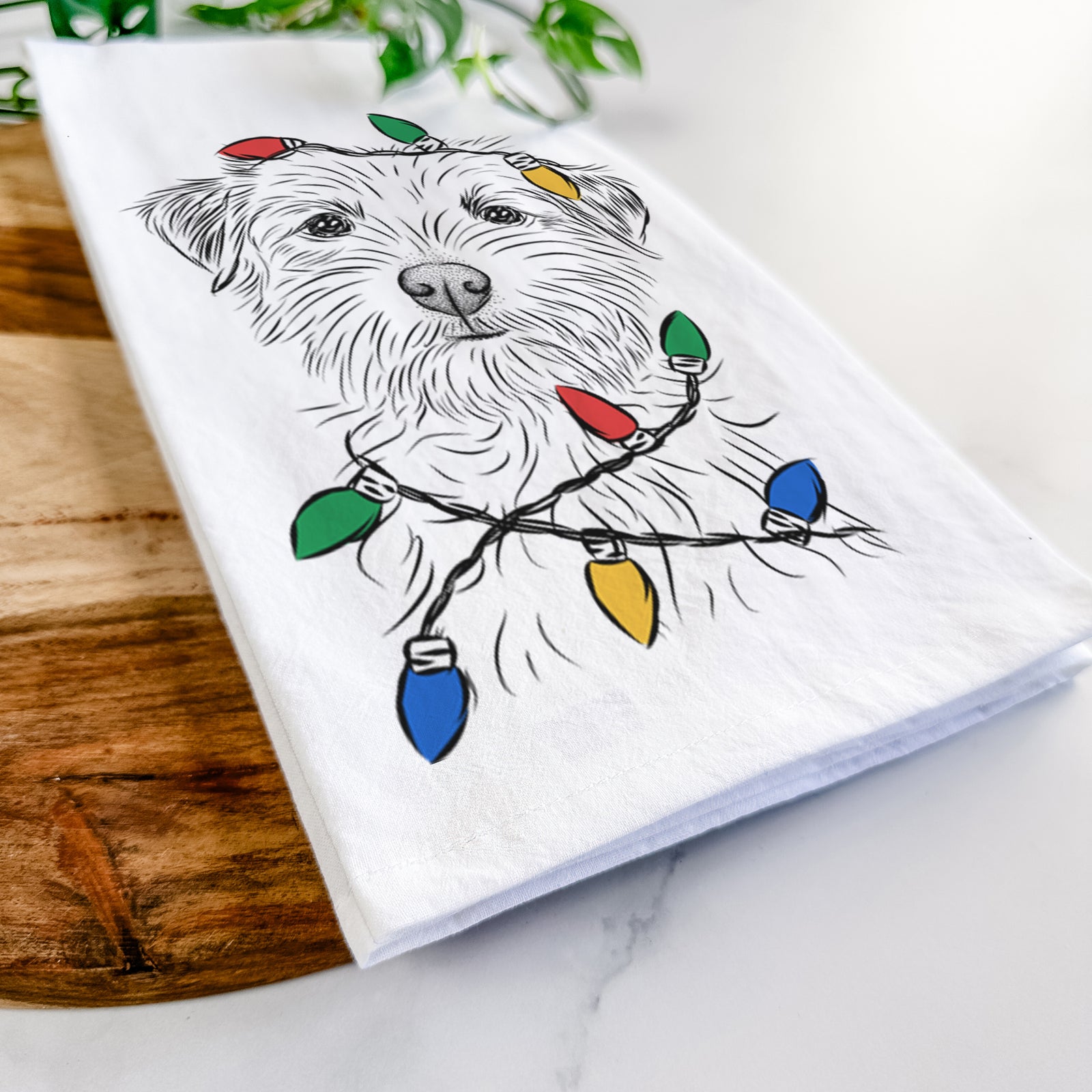 Hand-drawn sketch of Benjamin the Border Terrier wrapped in Christmas lights on a tea towel