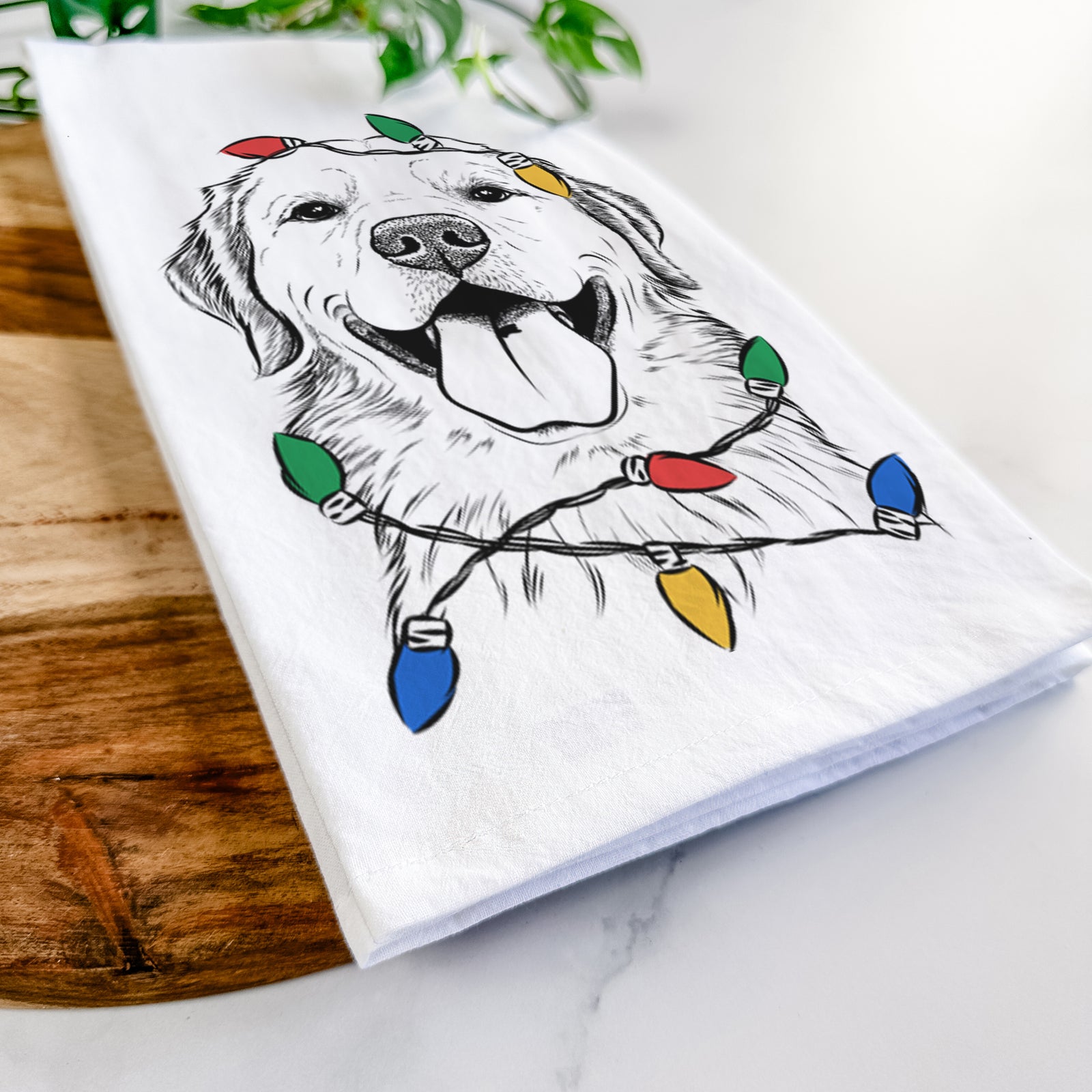 Hand-drawn sketch of Bennett the Golden Retriever wrapped in Christmas lights on a tea towel