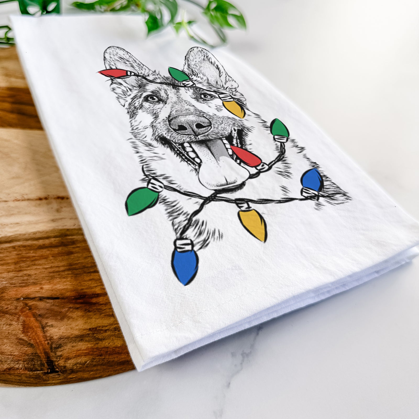 Hand-drawn sketch of Benson the German Shepherd wrapped in Christmas lights on a tea towel