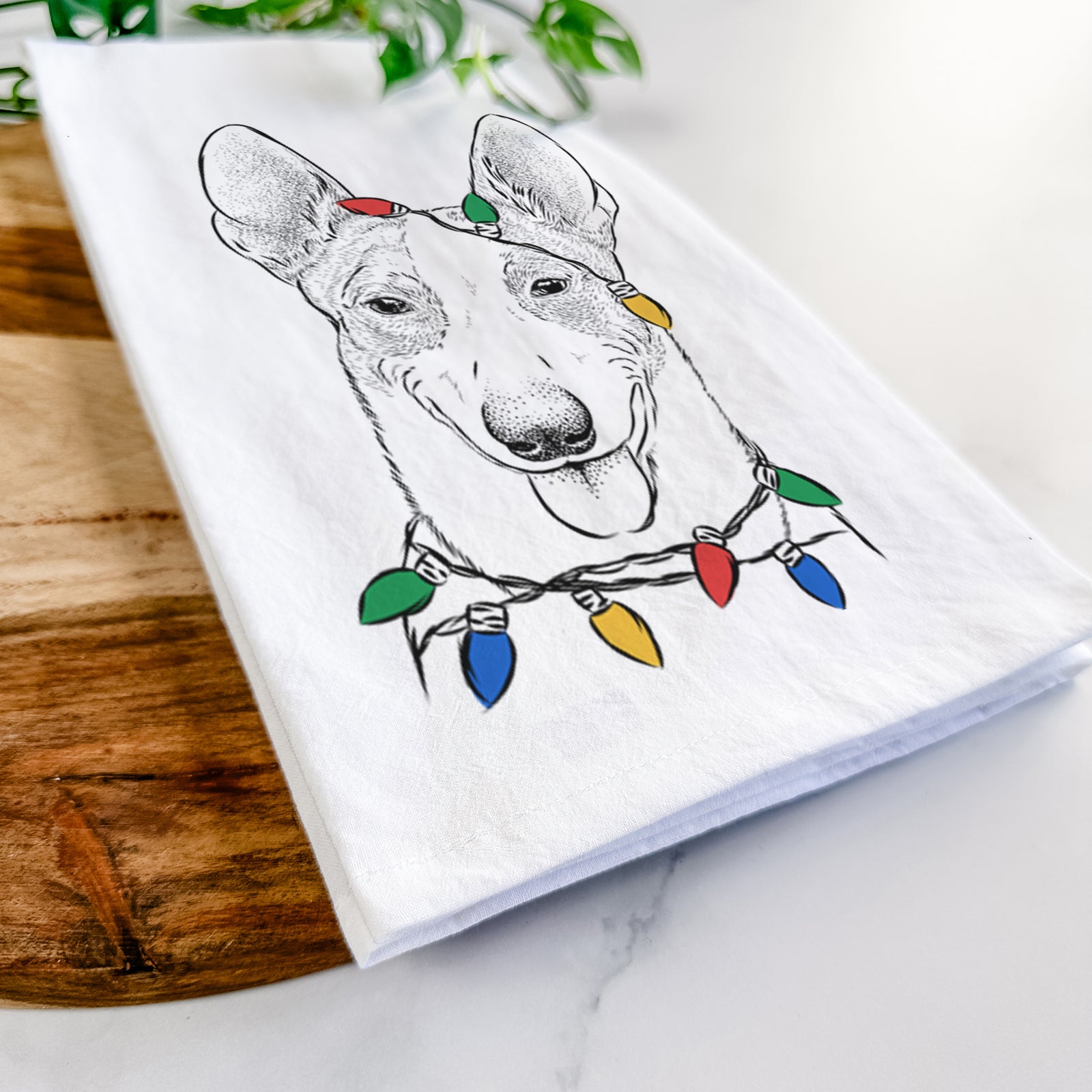 Hand-drawn sketch of Berlin the Carolina Dog wrapped in Christmas lights on a tea towel