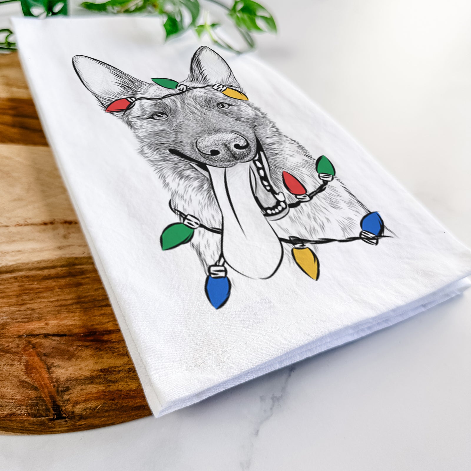 Hand-drawn sketch of Bessa the Dutch Shepherd wrapped in Christmas lights on a tea towel