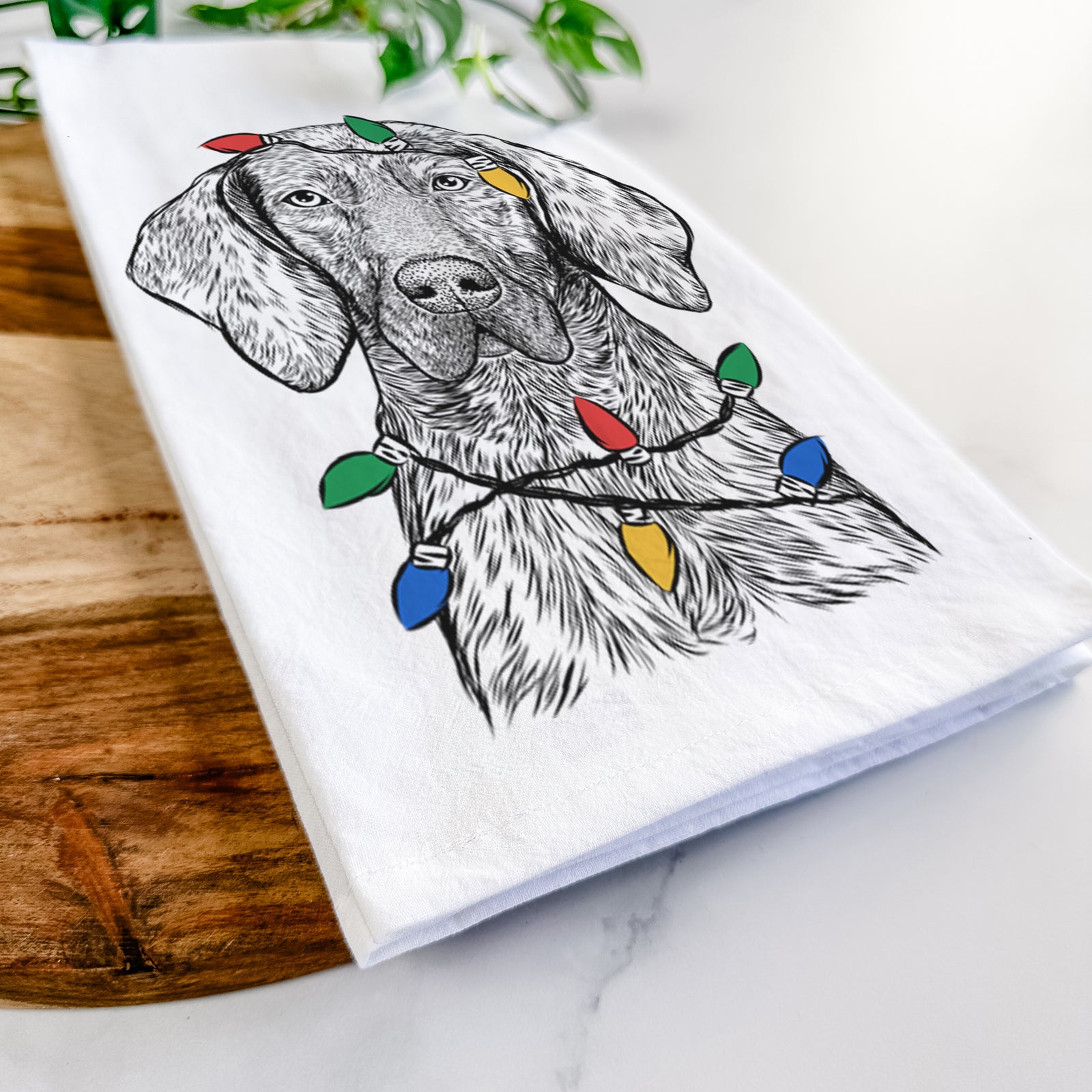 Hand-drawn sketch of Boone the Plott Hound wrapped in Christmas lights on a tea towel