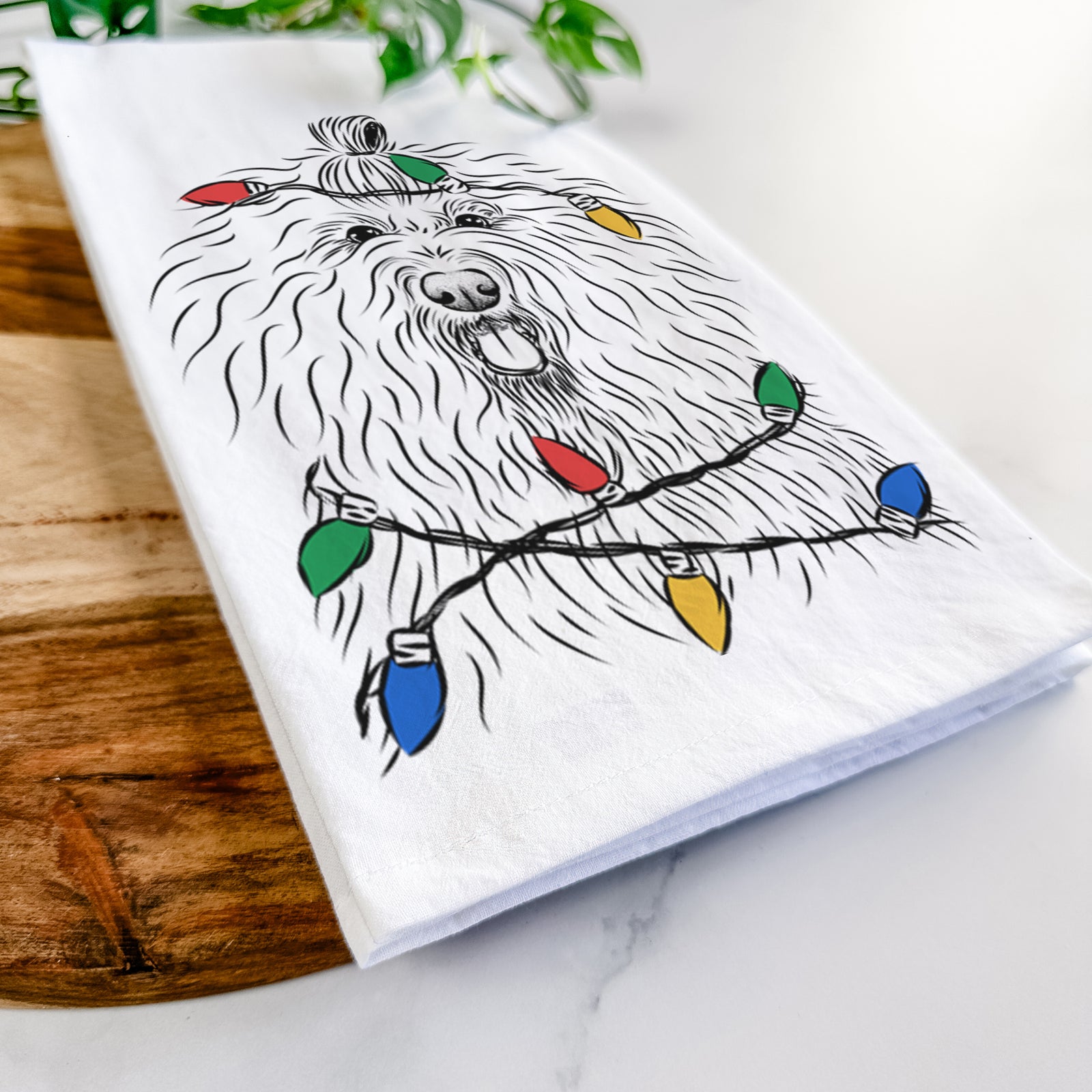 Hand-drawn sketch of Brody the Old English Sheepdog wrapped in Christmas lights on a tea towel