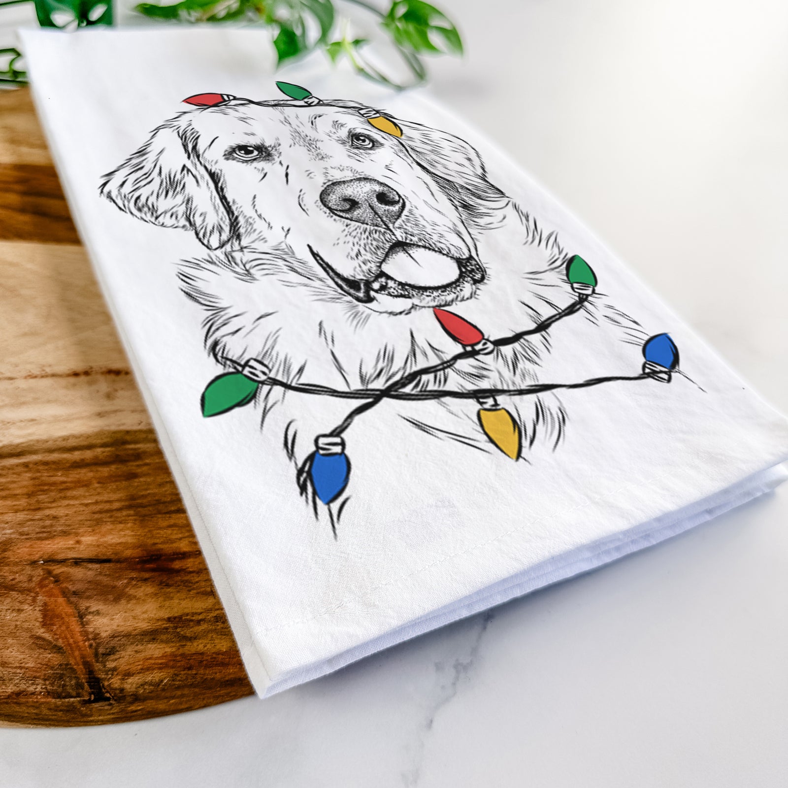 Hand-drawn sketch of Brophy the Great Pyrenees wrapped in Christmas lights on a tea towel