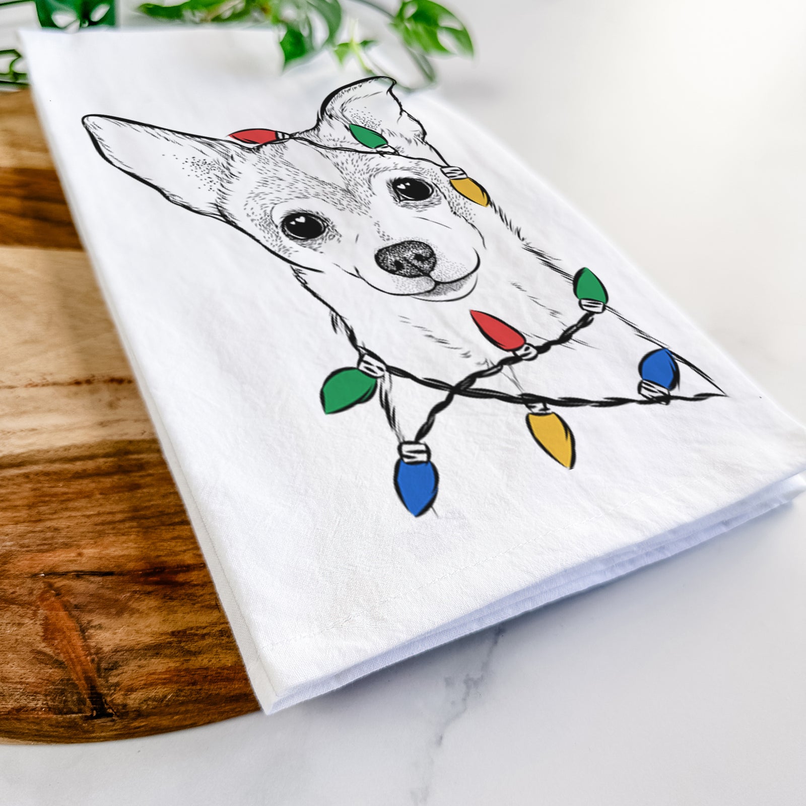 Hand-drawn sketch of Buggy the Chihuahua wrapped in Christmas lights on a tea towel