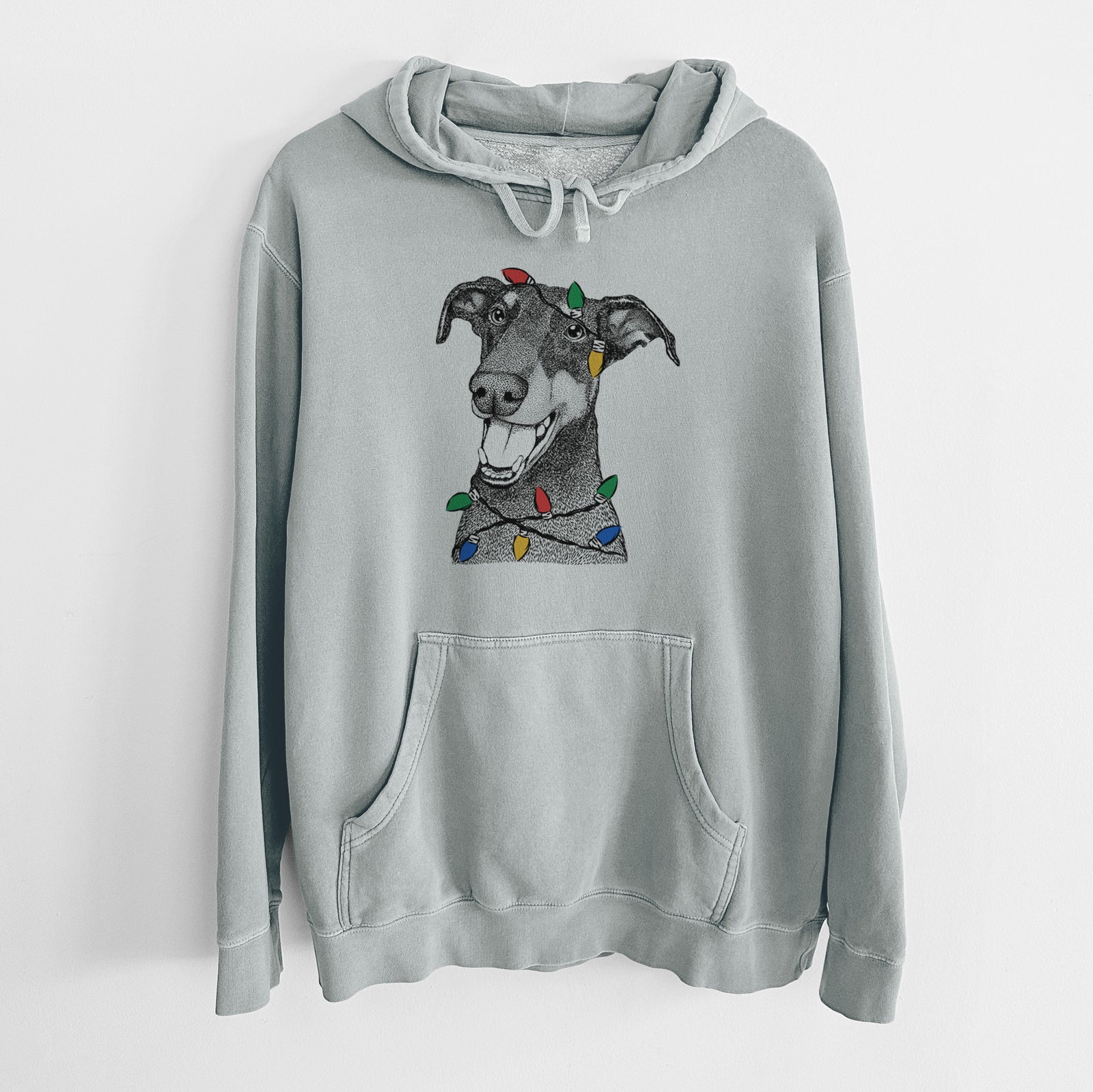 Hand-drawn sketch of Bunnie the Doberman Pinscher wrapped in Christmas lights on a Sage Unisex pigment dyed hoodie