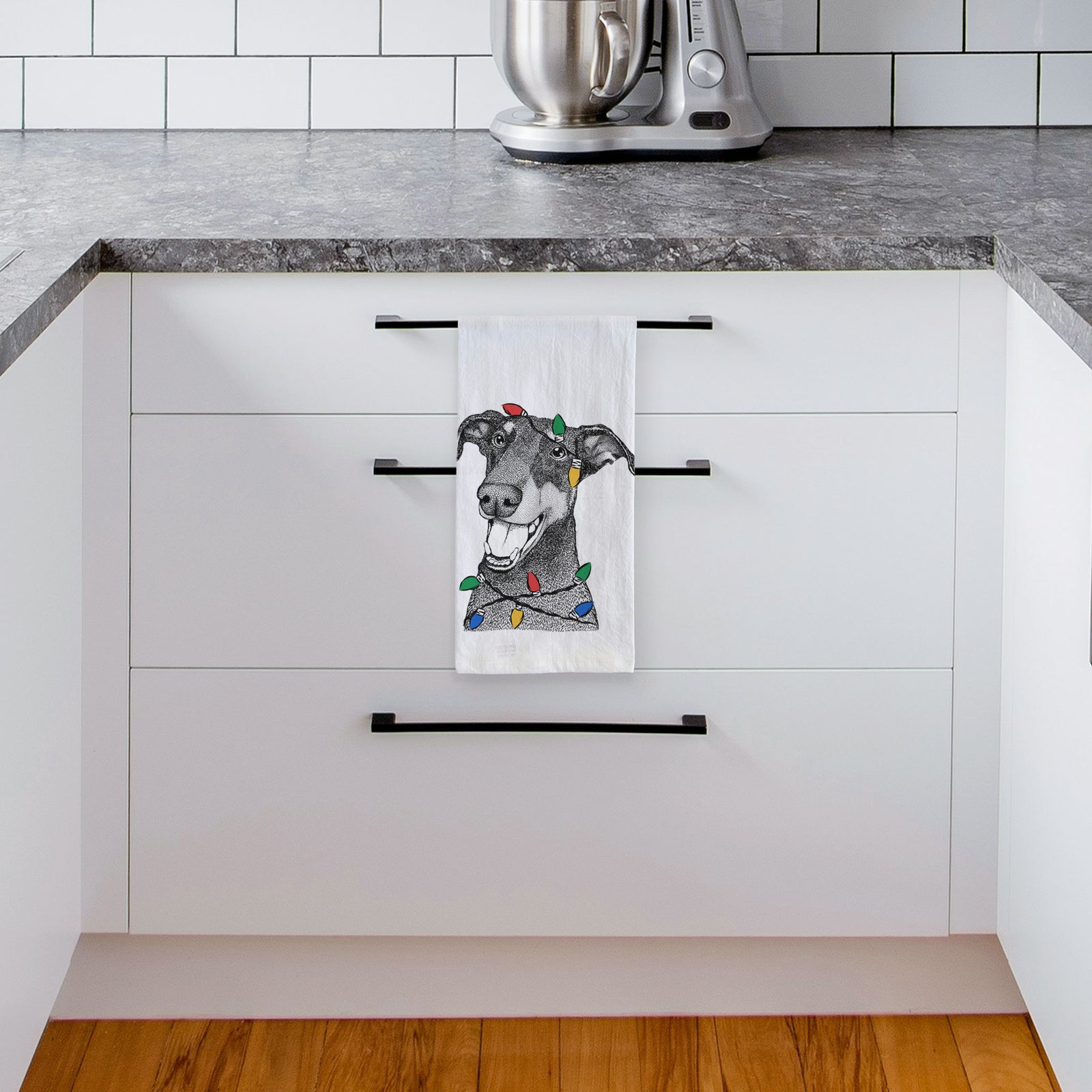 Hand-drawn sketch of Bunnie the Doberman Pinscher wrapped in Christmas lights on a tea towel, hanging on an oven door in a kitchen