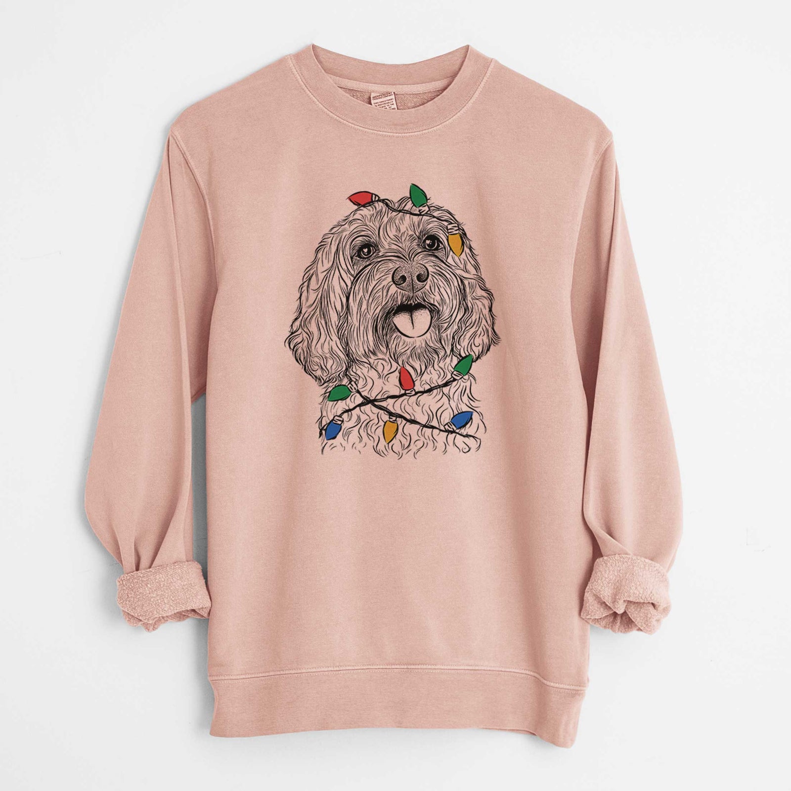 Hand-drawn sketch of Cali the Cavapoo wrapped in Christmas lights on a Dusty Pink Unisex pigment dyed crew sweatshirt