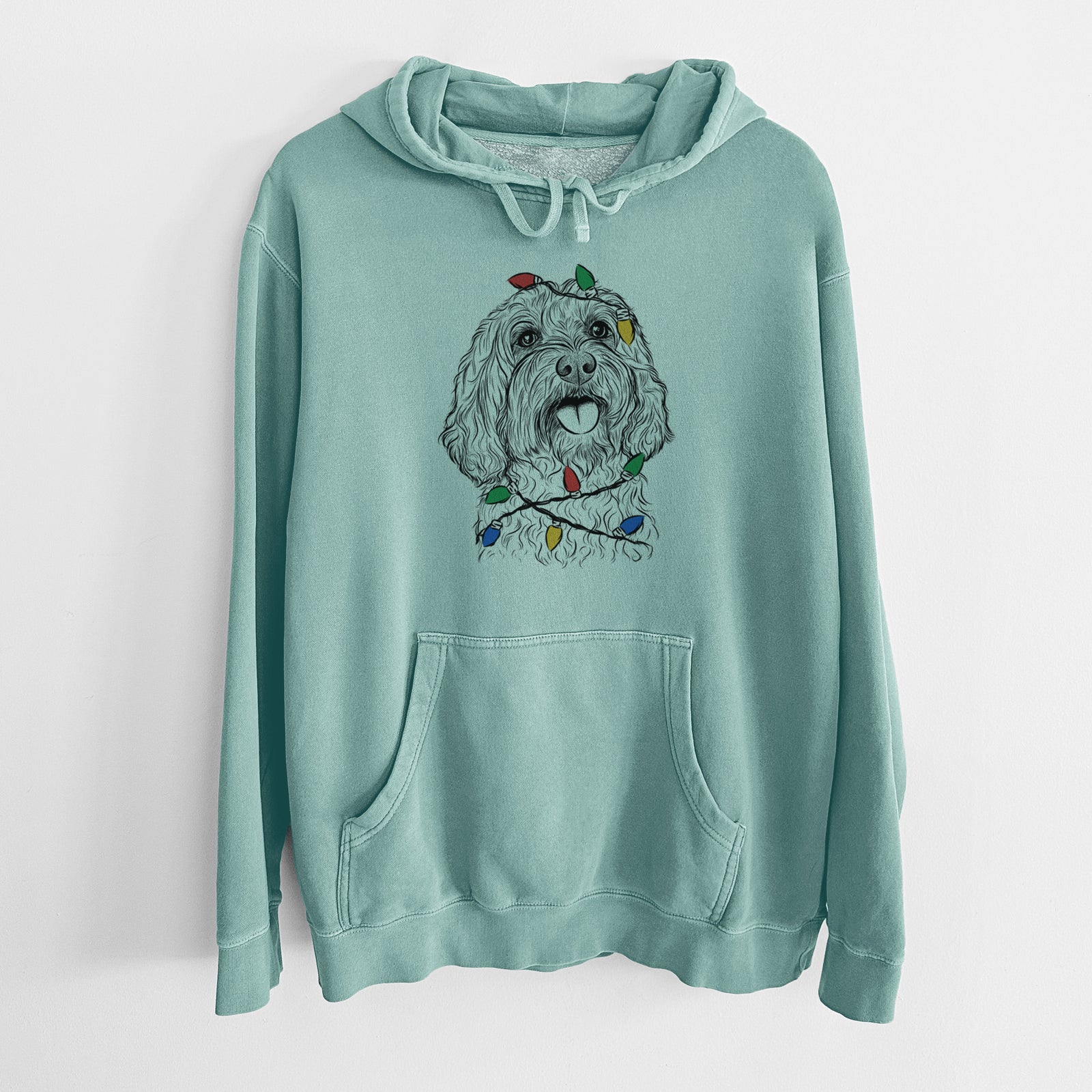 Hand-drawn sketch of Cali the Cavapoo wrapped in Christmas lights on a Mint Unisex pigment dyed hoodie