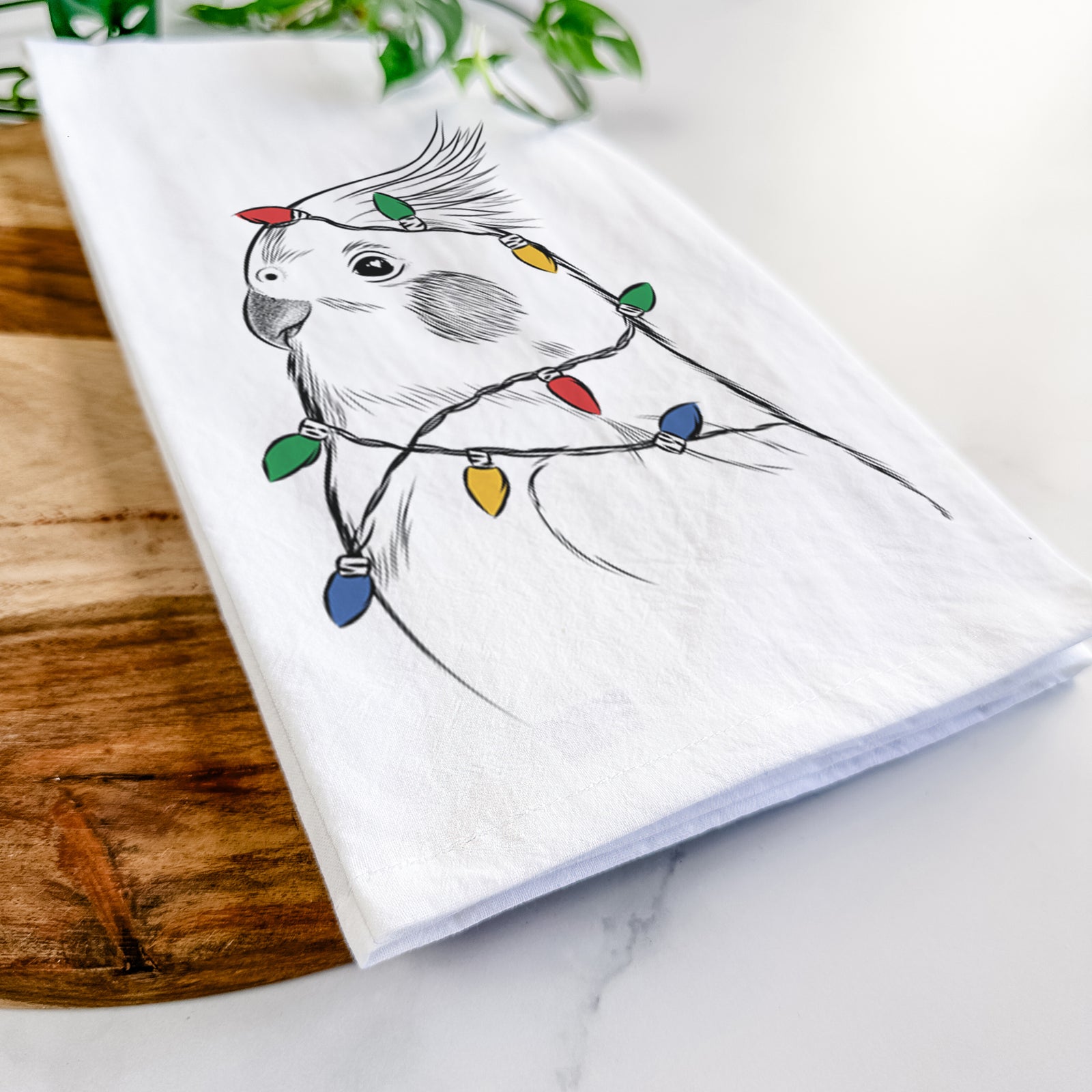 Hand-drawn sketch of Charlie the Cockatiel wrapped in Christmas lights on a tea towel
