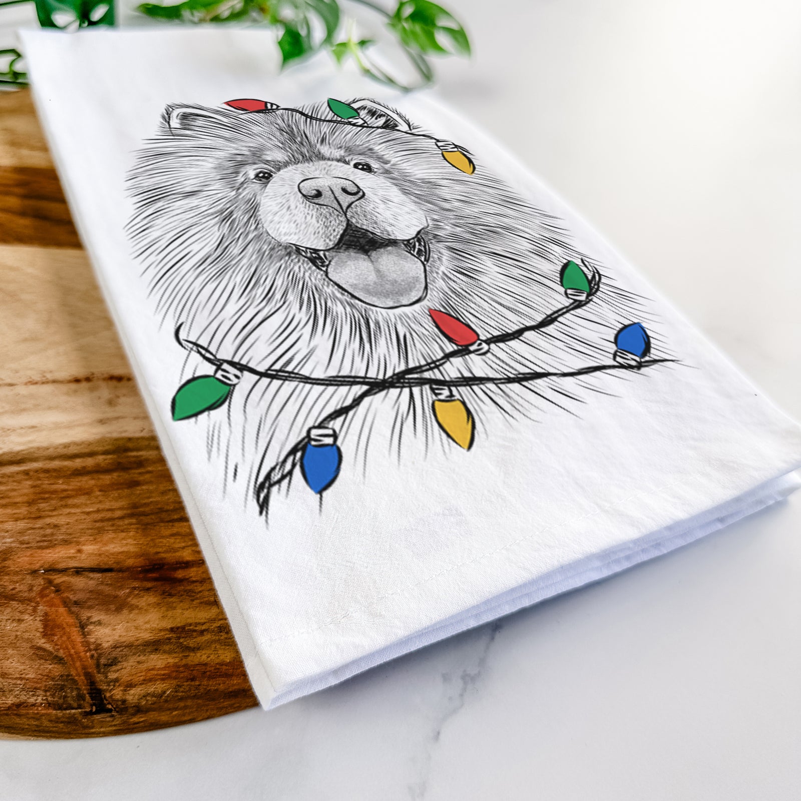 Hand-drawn sketch of Charming Charlie the Chow Chow wrapped in Christmas lights on a tea towel