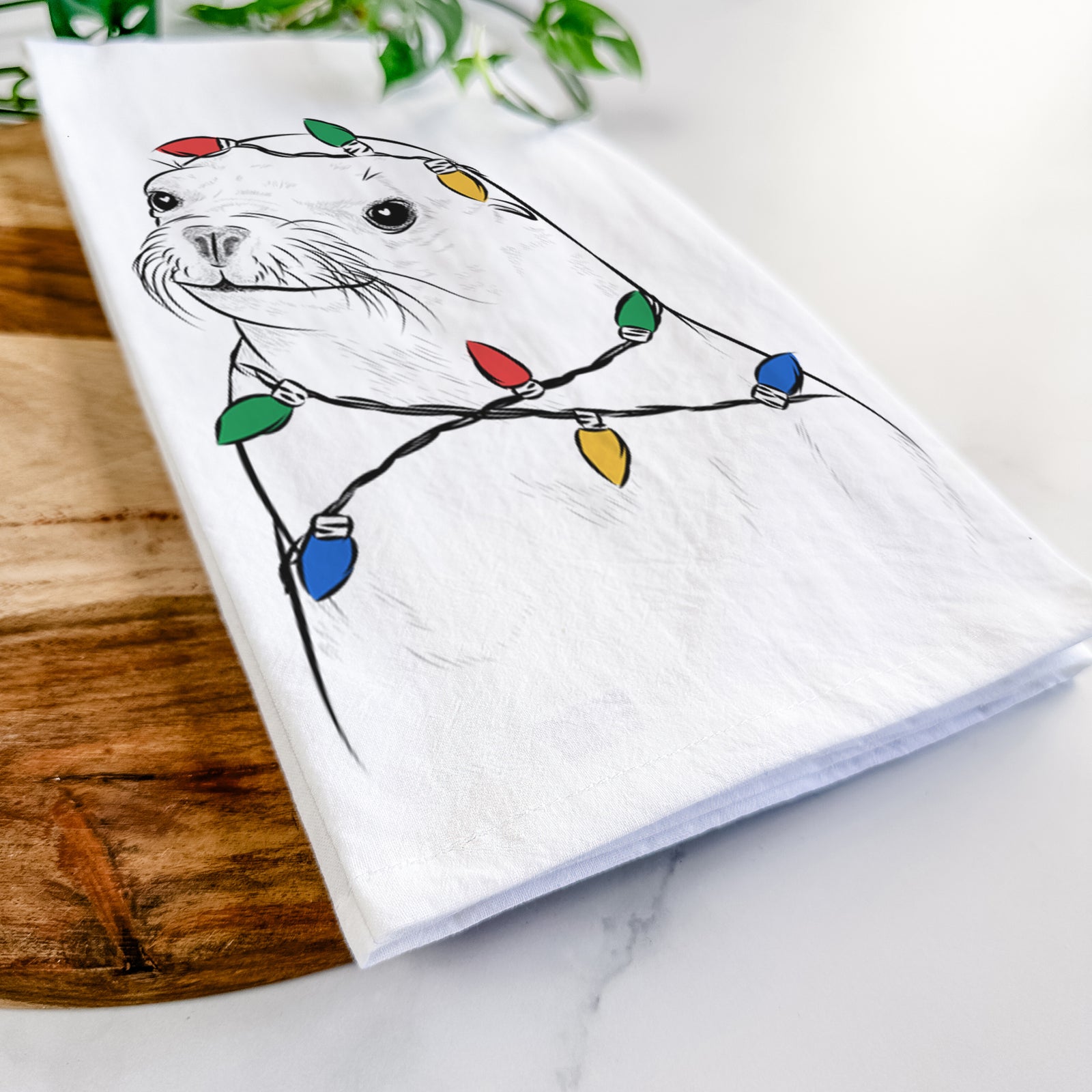 Hand-drawn sketch of Chip the California Sea Lion wrapped in Christmas lights on a tea towel