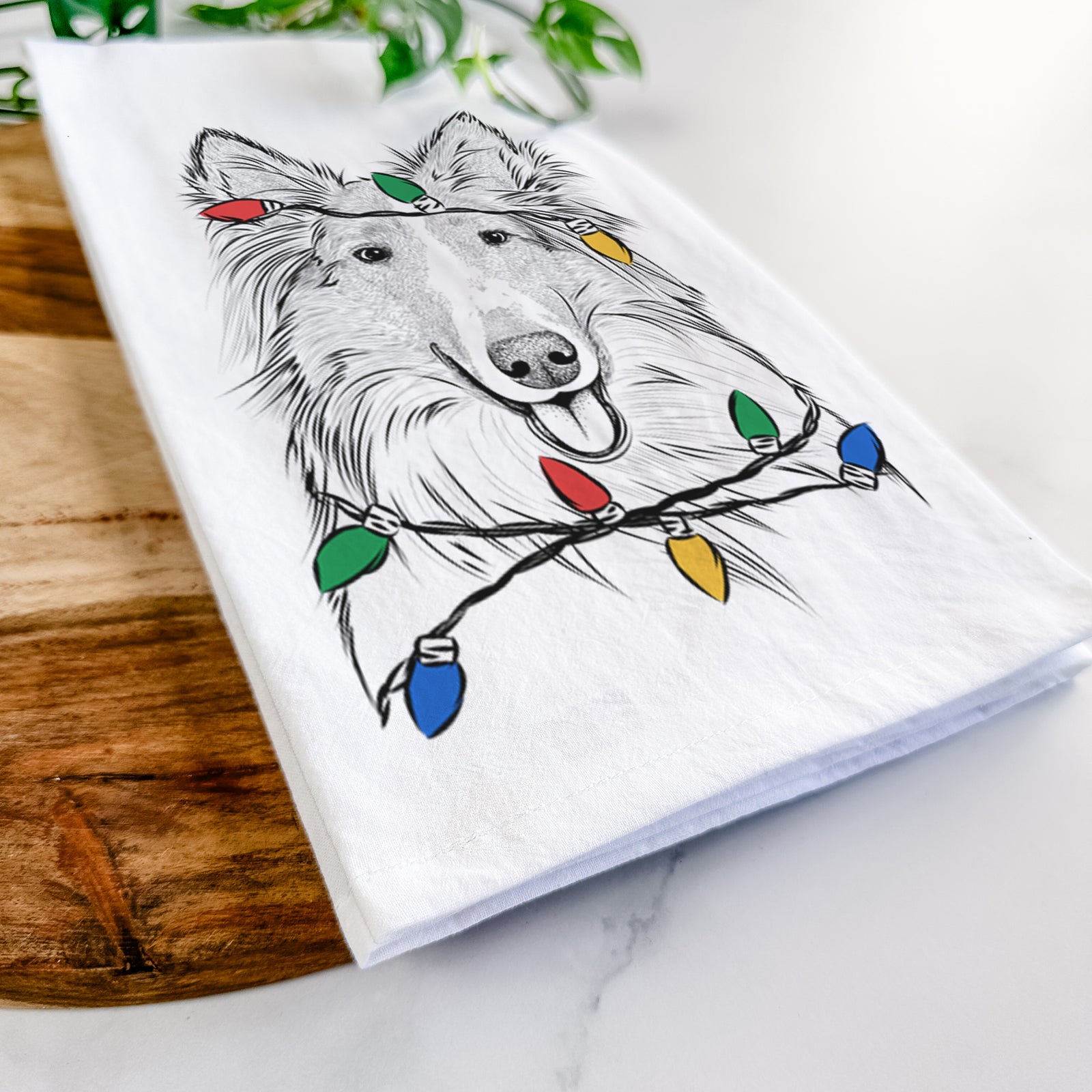 Hand-drawn sketch of Conrad the Rough Collie wrapped in Christmas lights on a tea towel