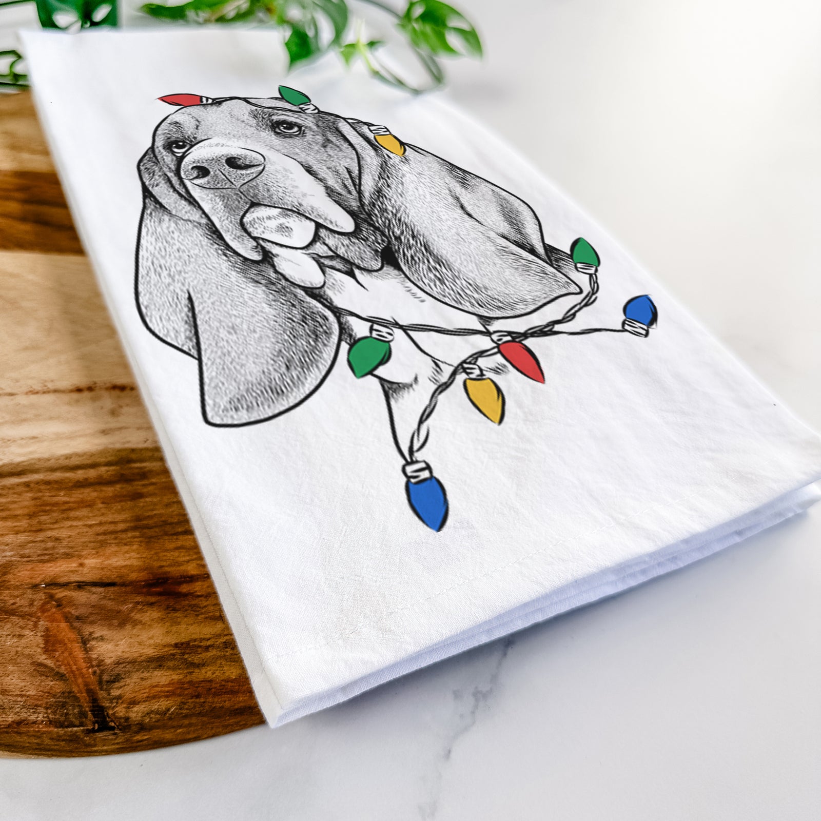 Hand-drawn sketch of Cooper the Basset Hound wrapped in Christmas lights on a tea towel