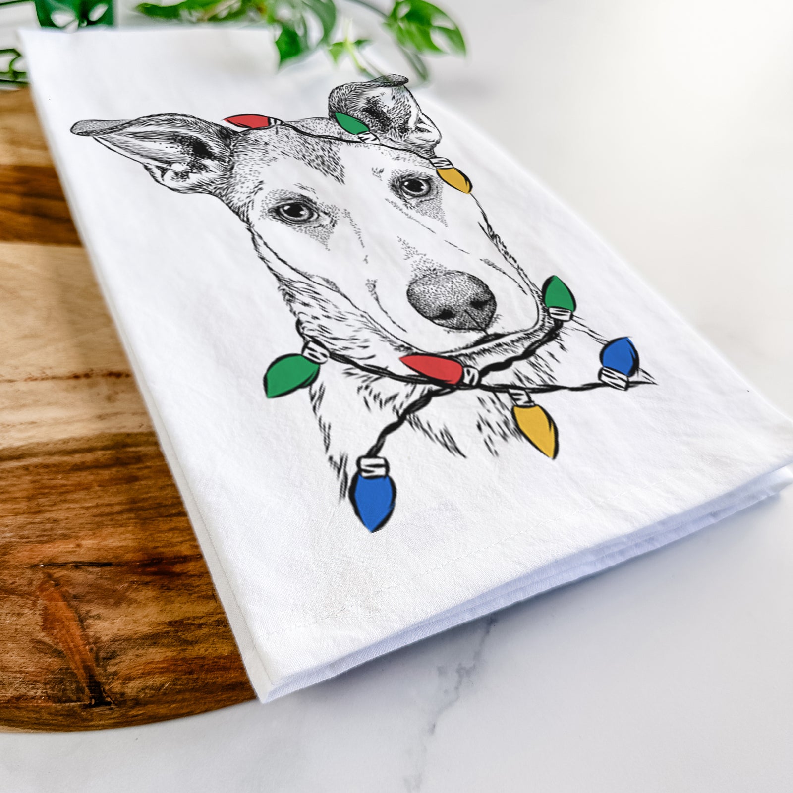 Hand-drawn sketch of Coral the Mixed Breed wrapped in Christmas lights on a tea towel