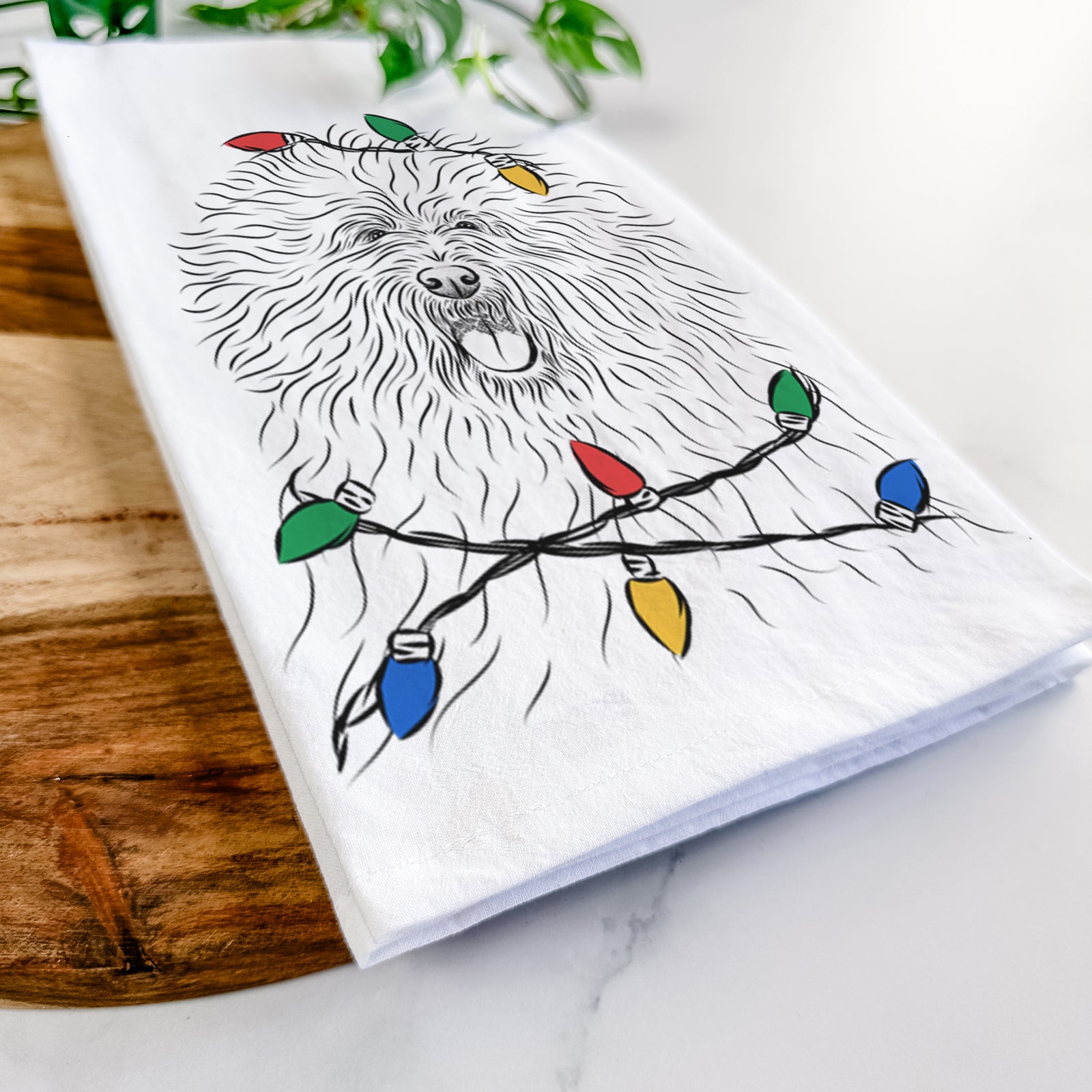 Hand-drawn sketch of Cozie the Old English Sheepdog wrapped in Christmas lights on a tea towel
