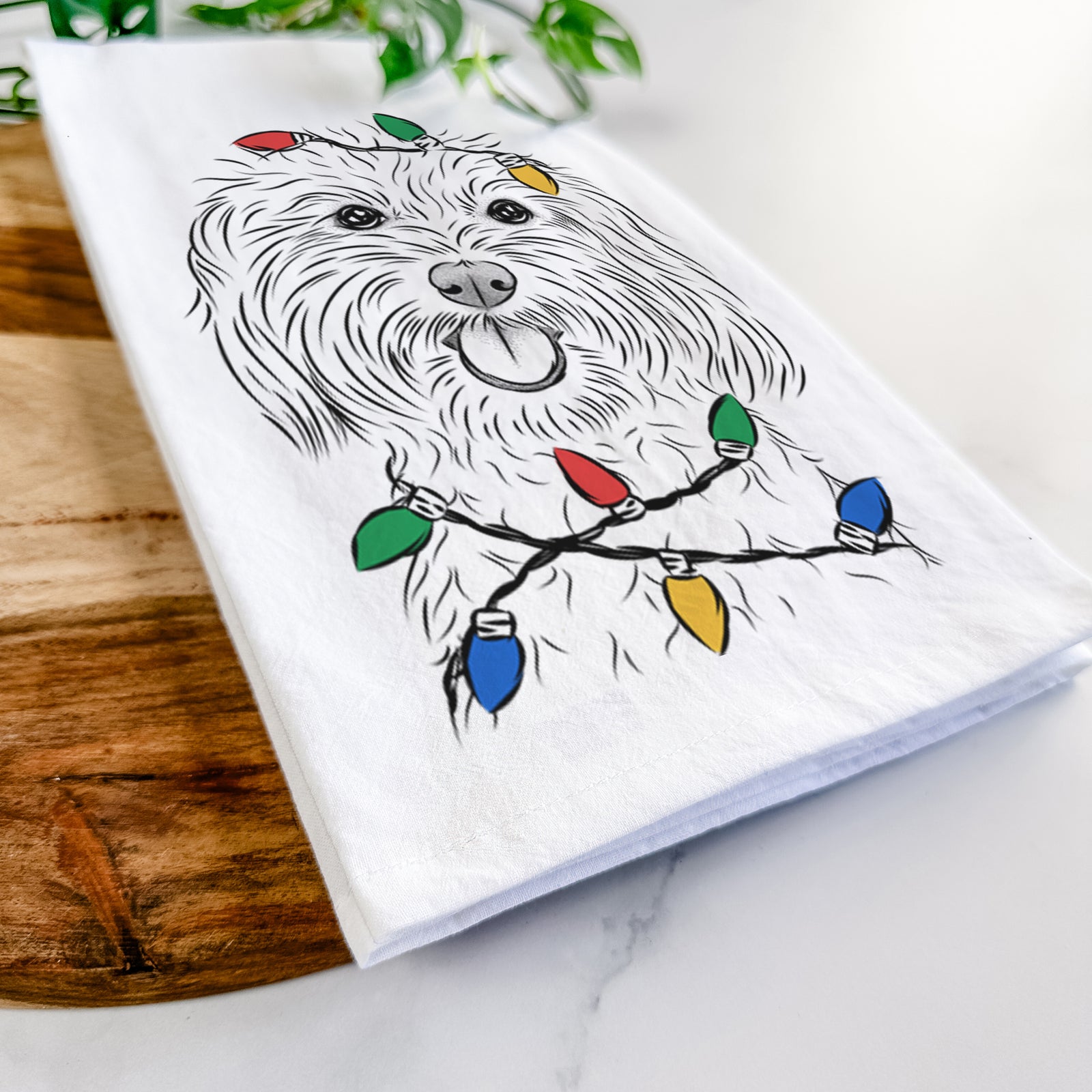 Hand-drawn sketch of Cuddles the Coton de Tulear wrapped in Christmas lights on a tea towel