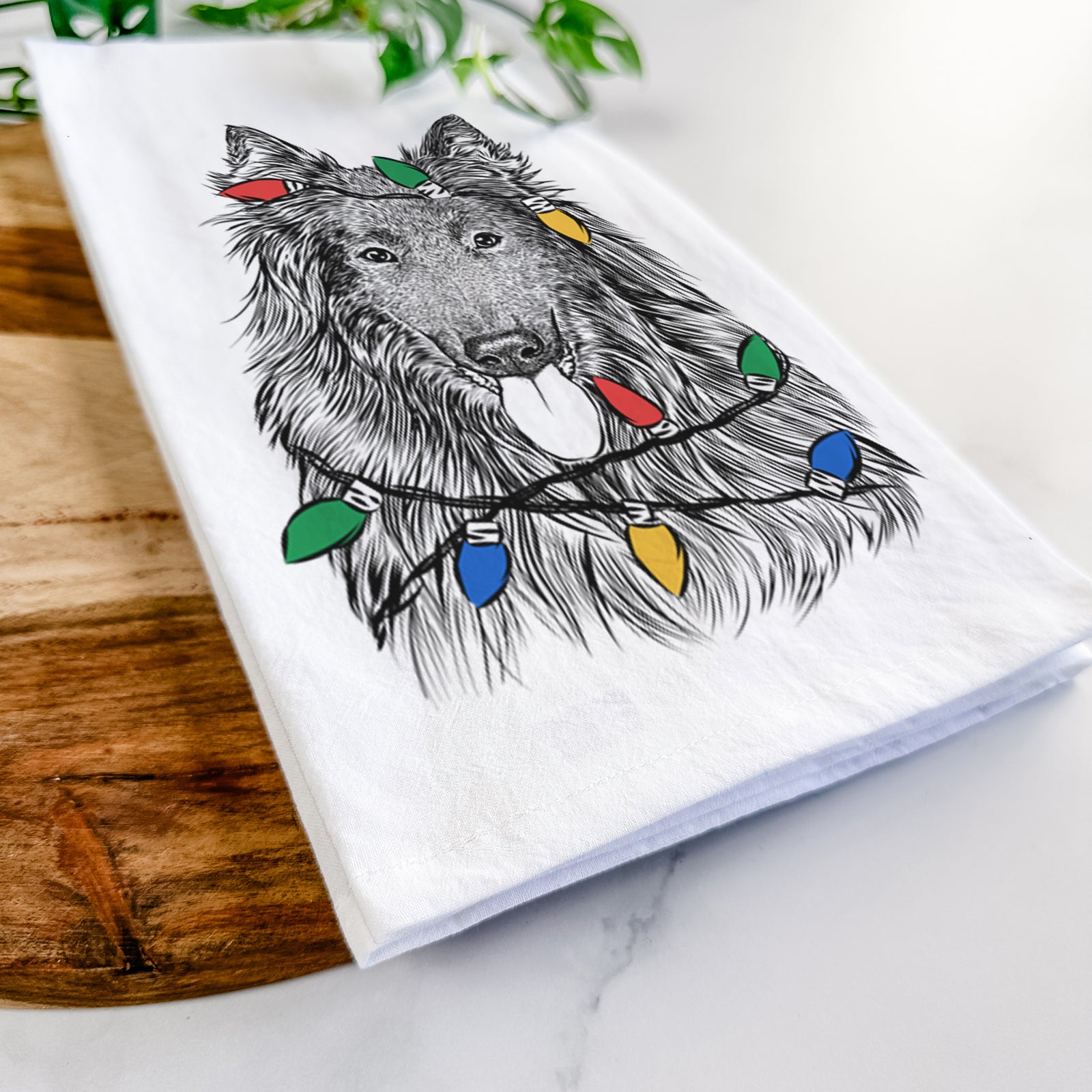 Hand-drawn sketch of Daan the Belgian Shepherd wrapped in Christmas lights on a tea towel