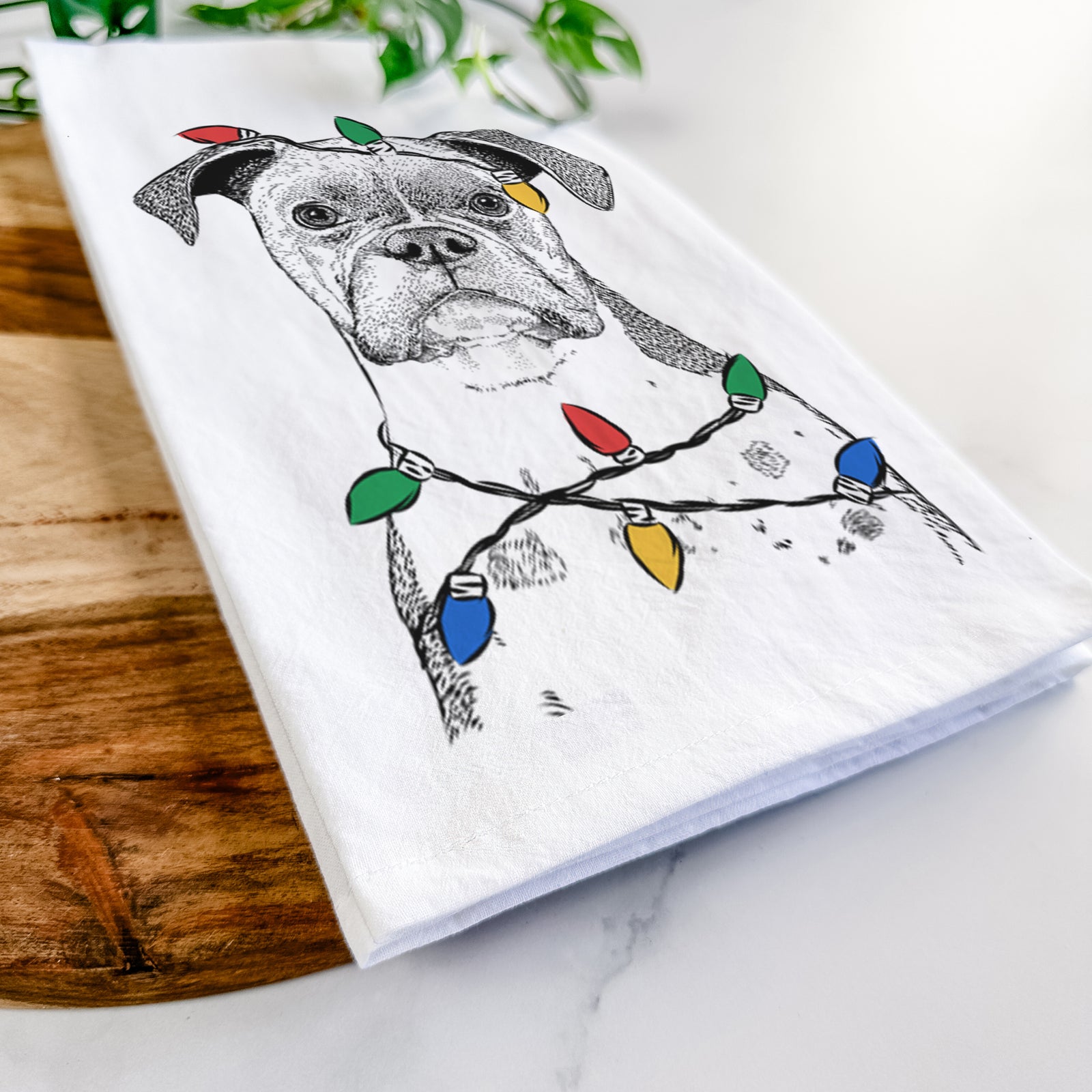 Hand-drawn sketch of Daisy the Boxer wrapped in Christmas lights on a tea towel