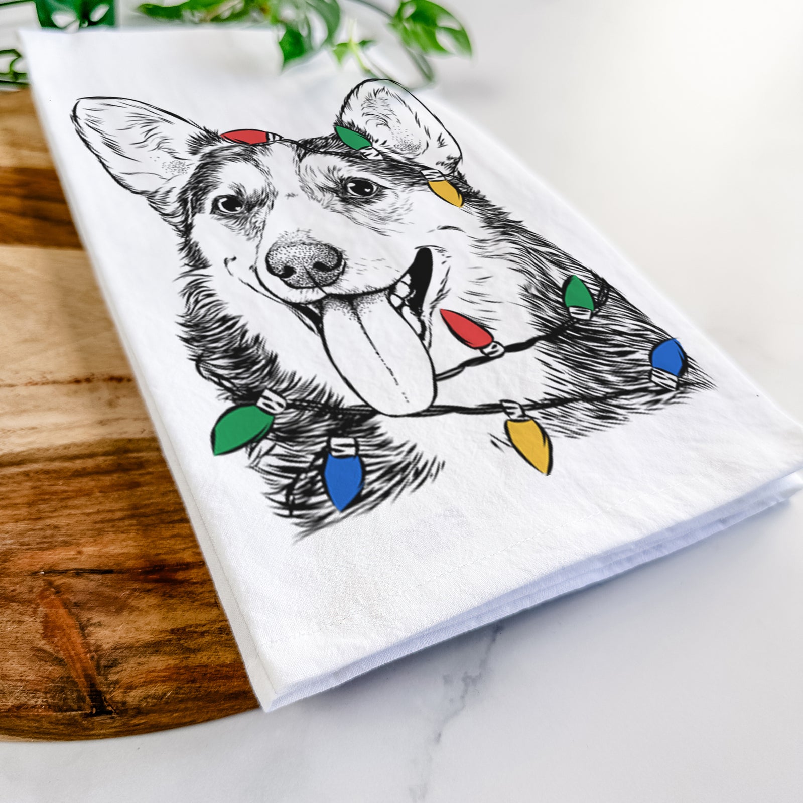 Hand-drawn sketch of Darma the Corgi wrapped in Christmas lights on a tea towel