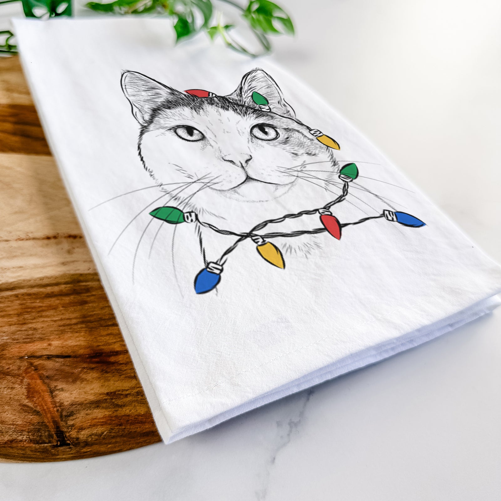 Hand-drawn sketch of Denver the Calico Cat wrapped in Christmas lights on a tea towel