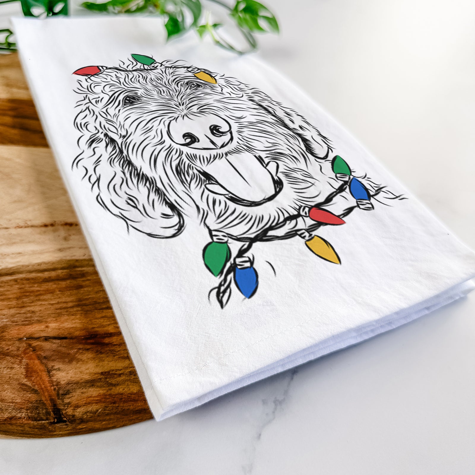 Hand-drawn sketch of Dixie the Doodle wrapped in Christmas lights on a tea towel