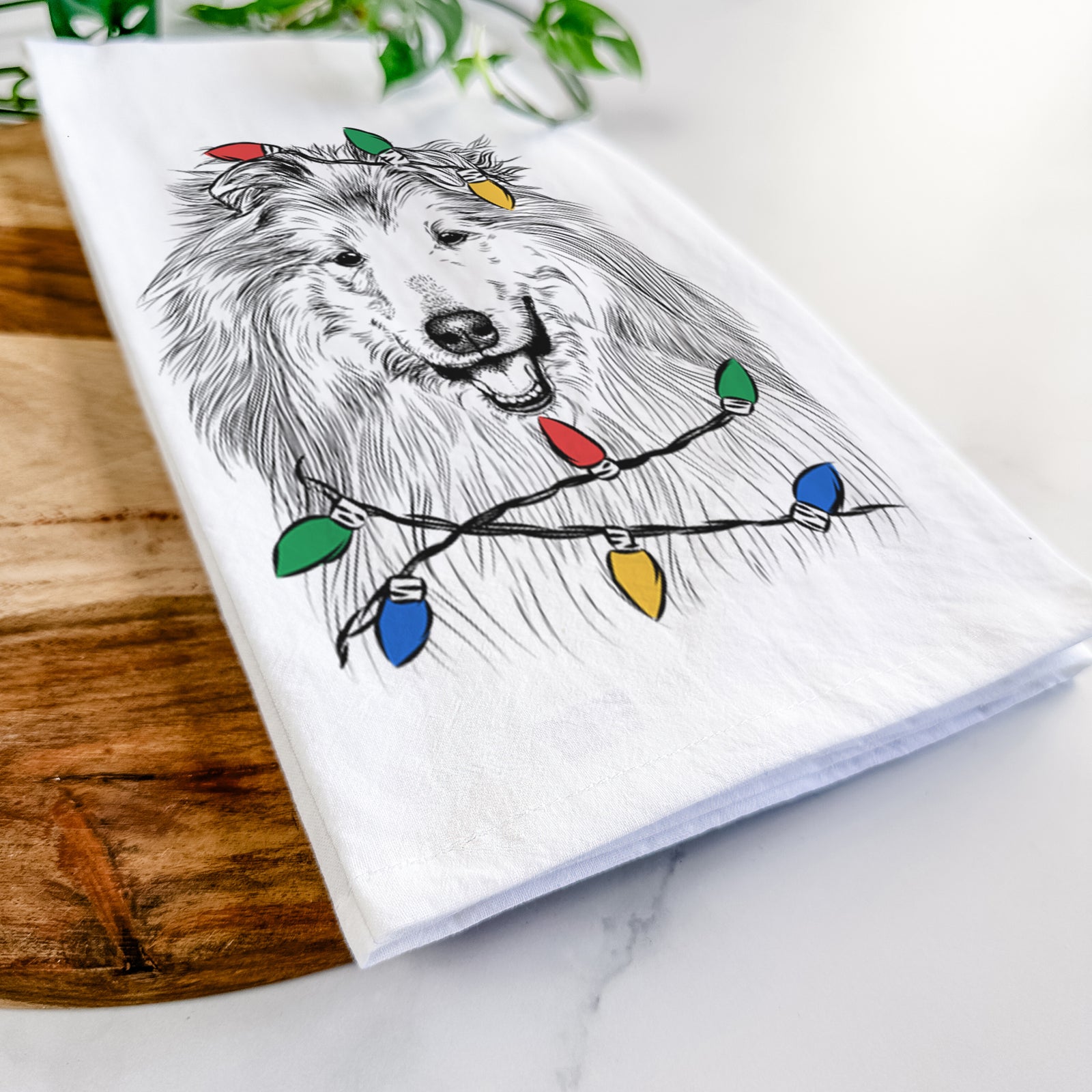 Hand-drawn sketch of Donnan the Rough Collie wrapped in Christmas lights on a tea towel