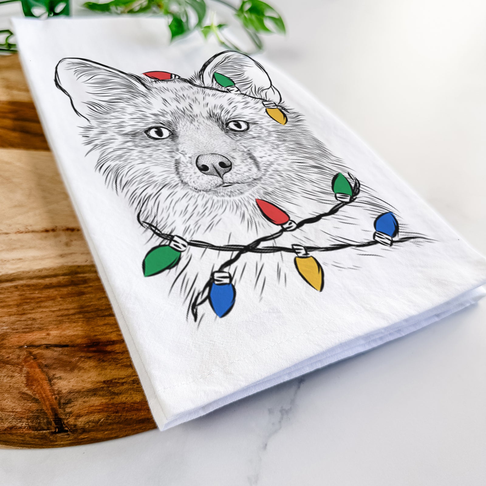 Hand-drawn sketch of Drax the Red Fox wrapped in Christmas lights on a tea towel