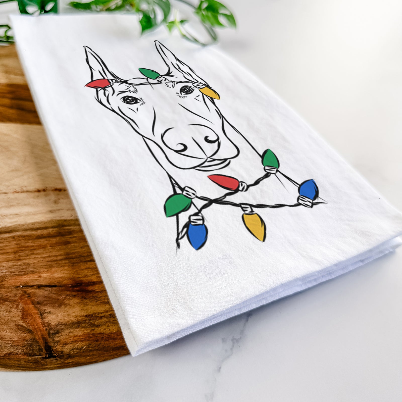 Hand-drawn sketch of Duke the Doberman Pinscher wrapped in Christmas lights on a tea towel