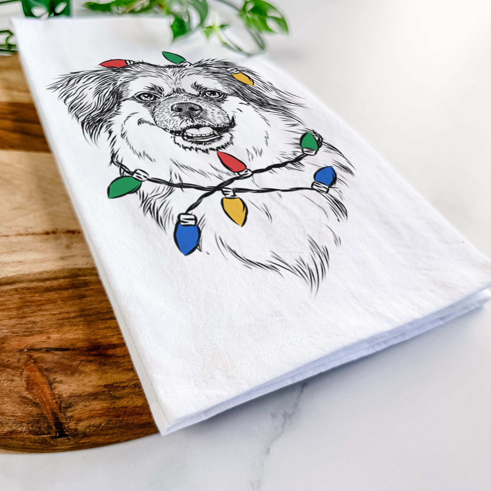 Hand-drawn sketch of Ed the Tibetan Spaniel wrapped in Christmas lights on a tea towel