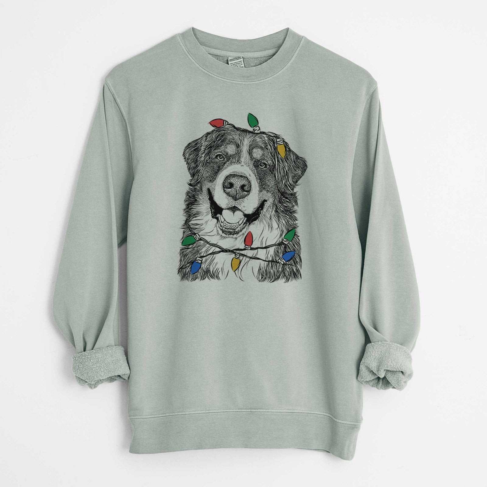 Hand-drawn sketch of Eiger the Bernese Mountain Dog wrapped in Christmas lights on a Sage Unisex pigment dyed crew sweatshirt