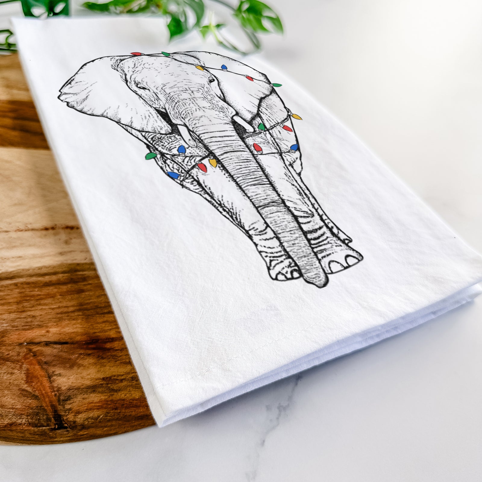 Hand-drawn sketch of Ella the Elephant wrapped in Christmas lights on a tea towel