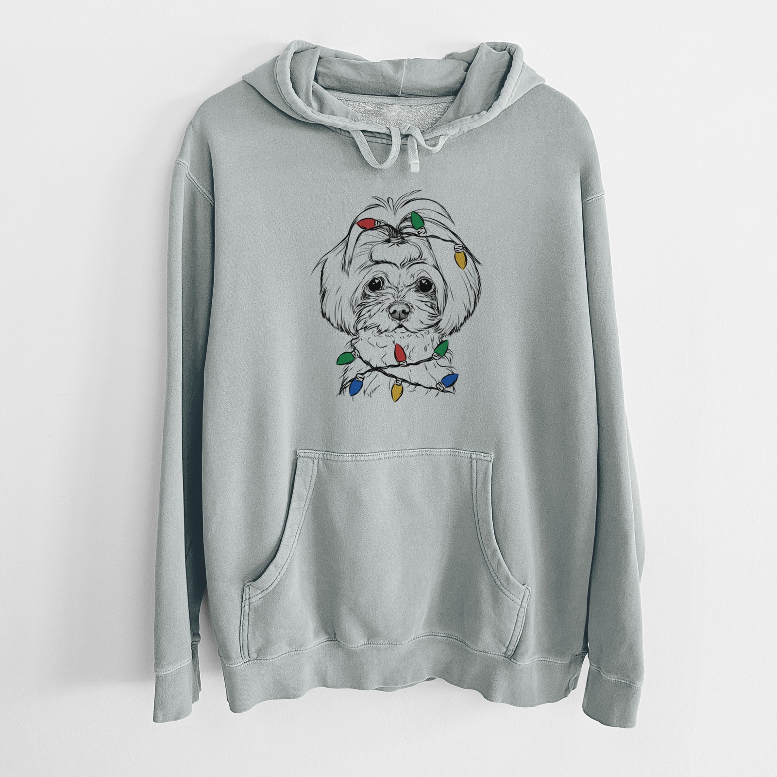 Hand-drawn sketch of Ellie the Maltese wrapped in Christmas lights on a Sage Unisex pigment dyed hoodie